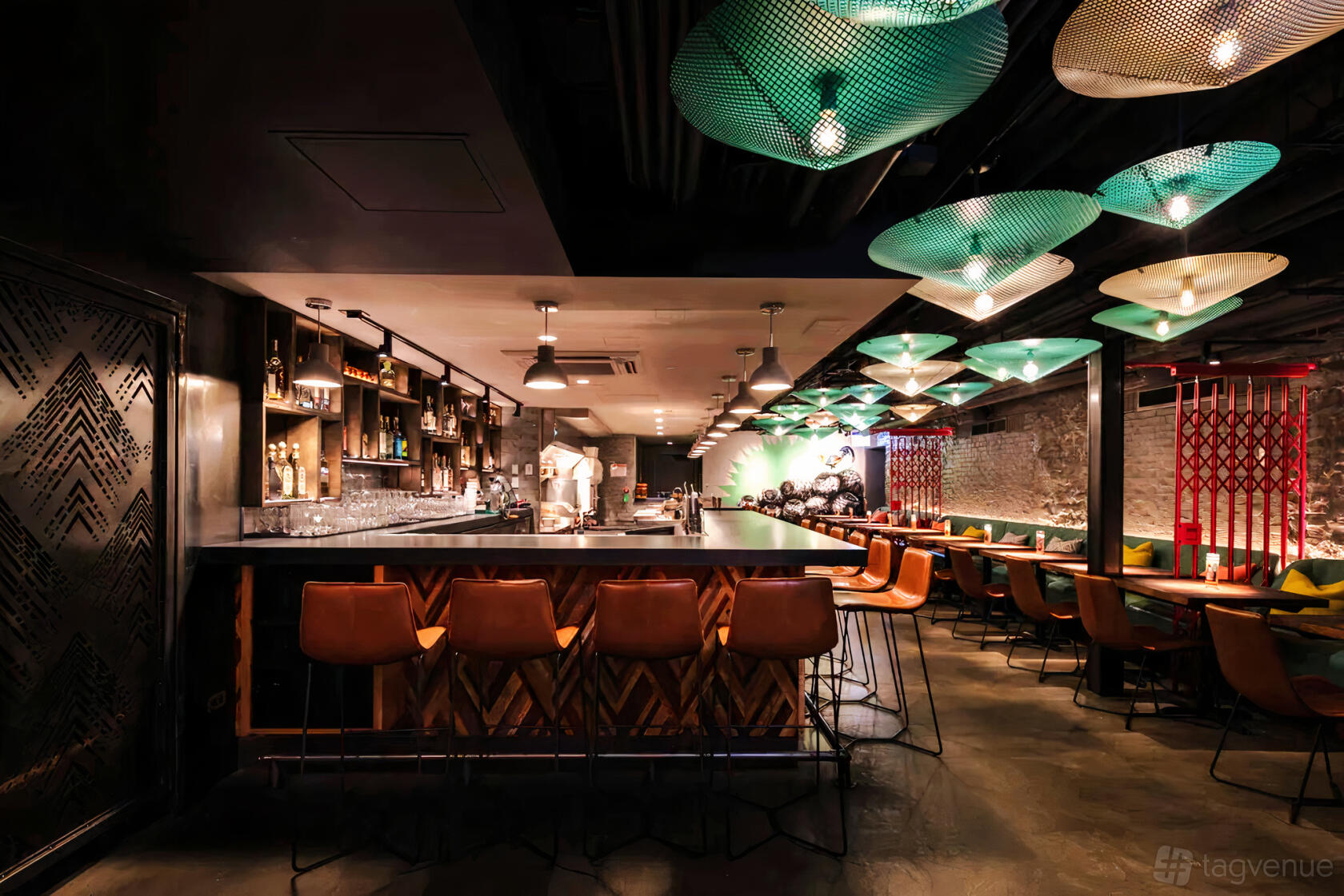 A bar with leather barstools, pendant lighting, and a long wooden counter at Bar Sotano.