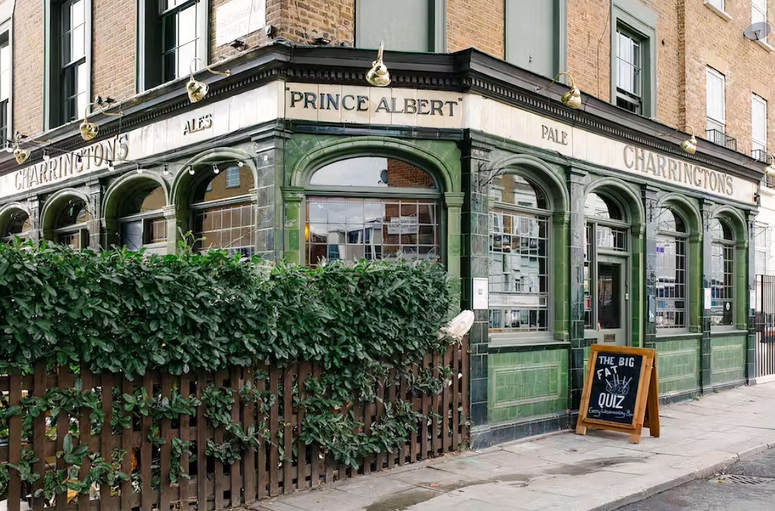A pub with green glazed tile exterior, large windows, and sidewalk chalkboard sign at The Prince Albert.