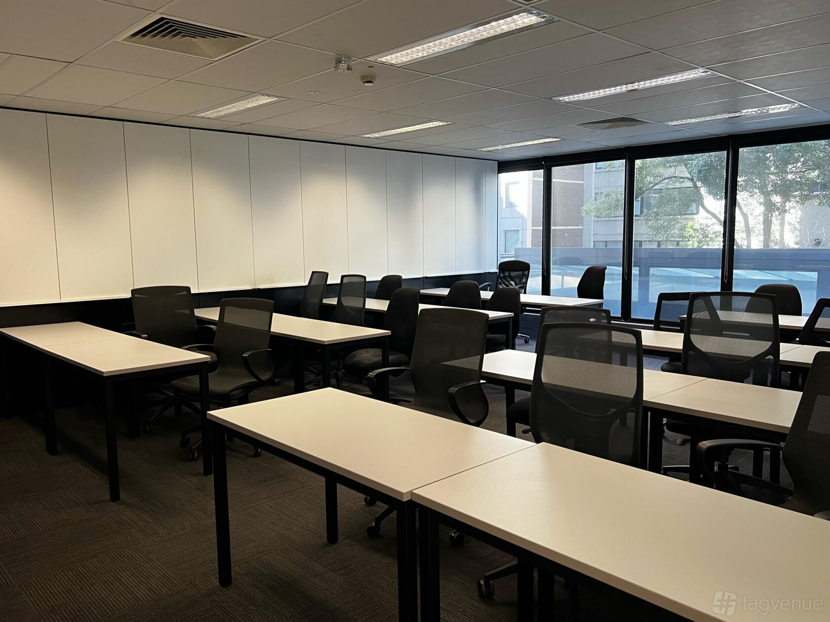 A classroom with rows of black chairs, white desks, and floor-to-ceiling windows at Thames International College.