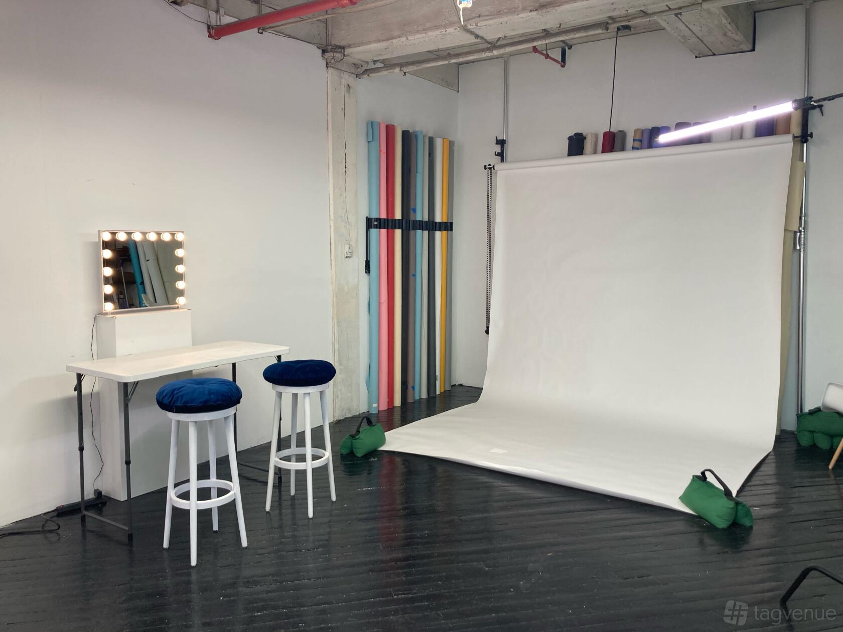A photo and film studio with a white backdrop, vanity mirror, and colored background rolls at Joco Media.