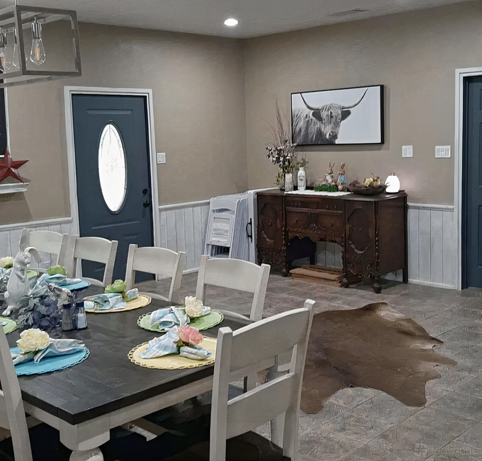 A farmhouse dining room with a long wooden table, white chairs, decorative place settings, and rustic decor at Lonesome Dove.