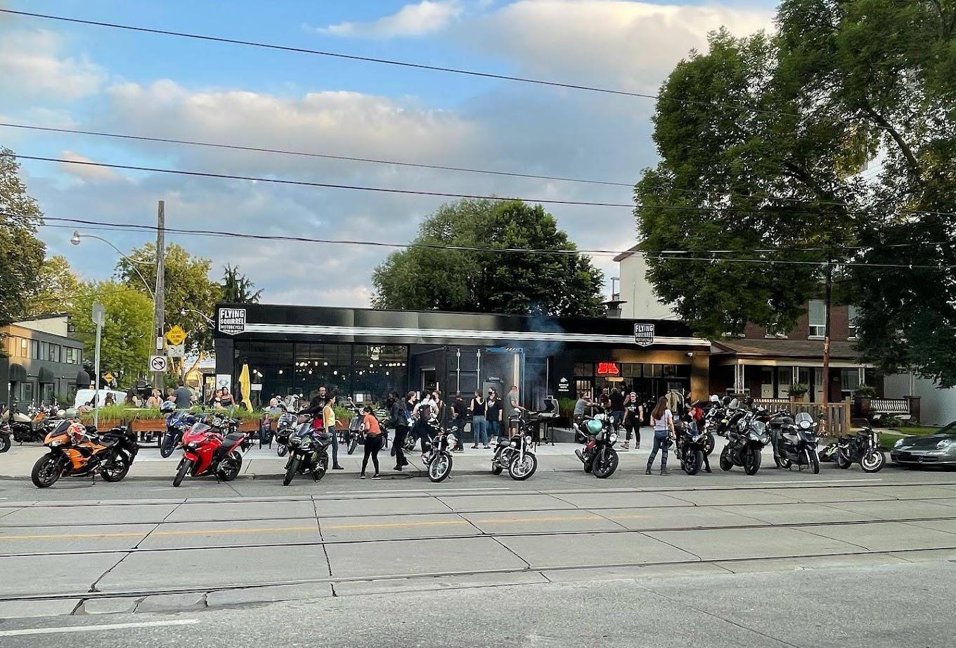 A terrace cafe with outdoor seating and parked motorcycles in front at Flying Squirrel Motorcycle Co.