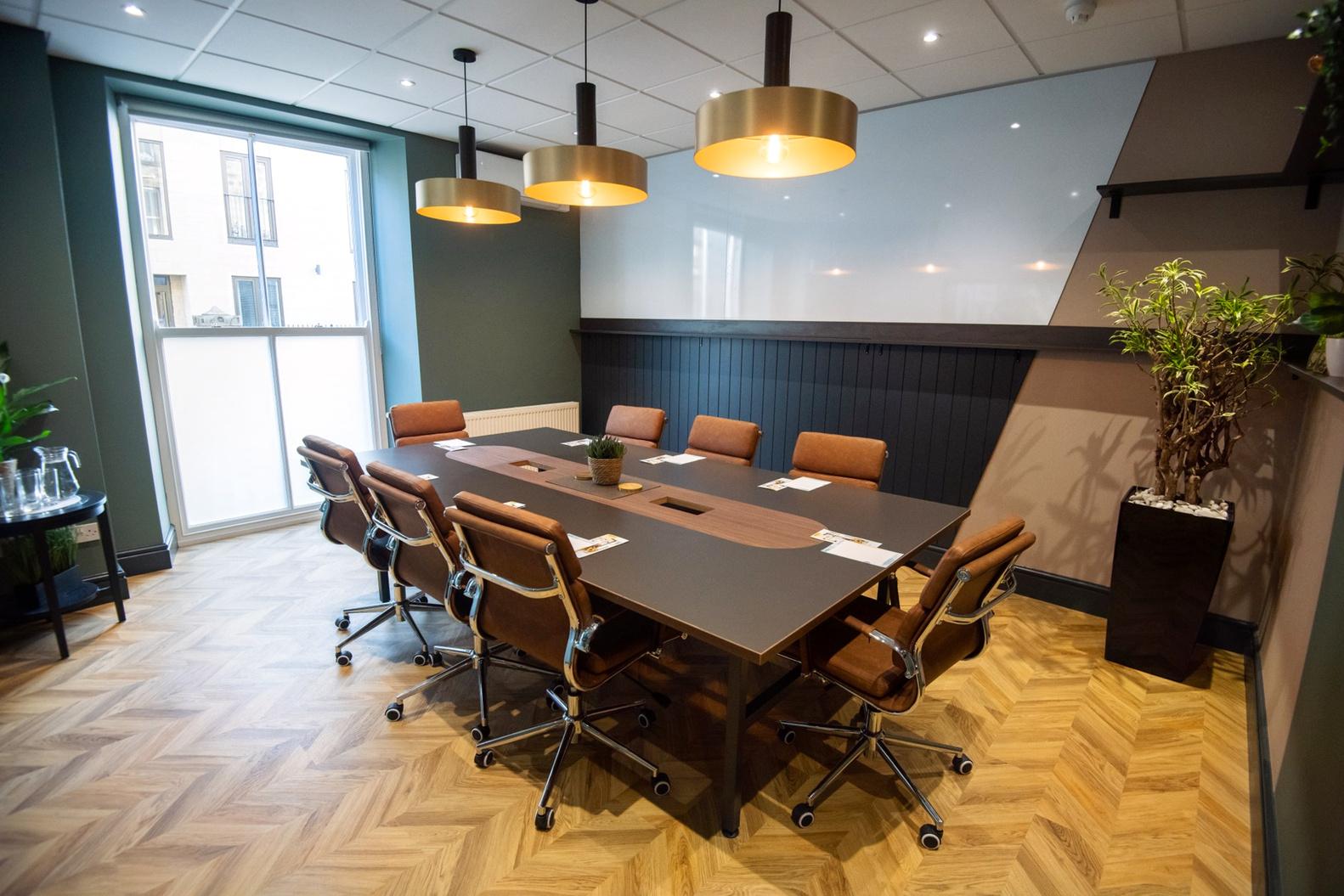 A meeting room with a large conference table, brown swivel chairs, pendant lights, and a whiteboard wall at Wizu Workspace - Harrogate - Royal House.