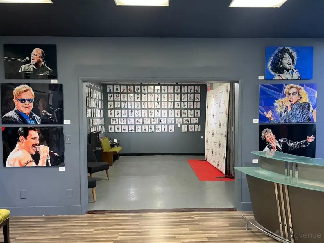 A gallery with colorful musician portraits on gray walls and a reception desk at Portnoy Gallery.