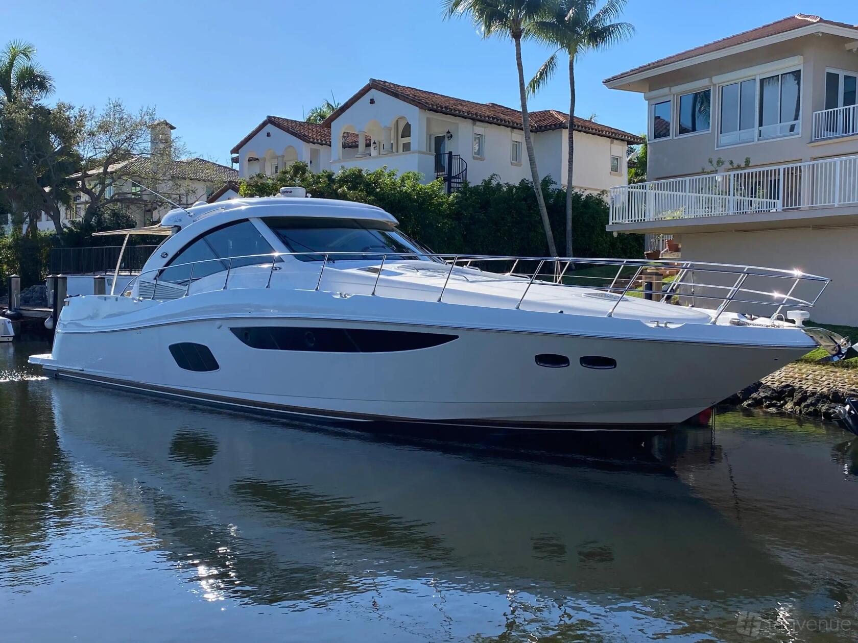 A sleek white boat with large windows, stainless steel railings, and a spacious deck at Lots Of Yachts/Lots Of Spots South Florida.
