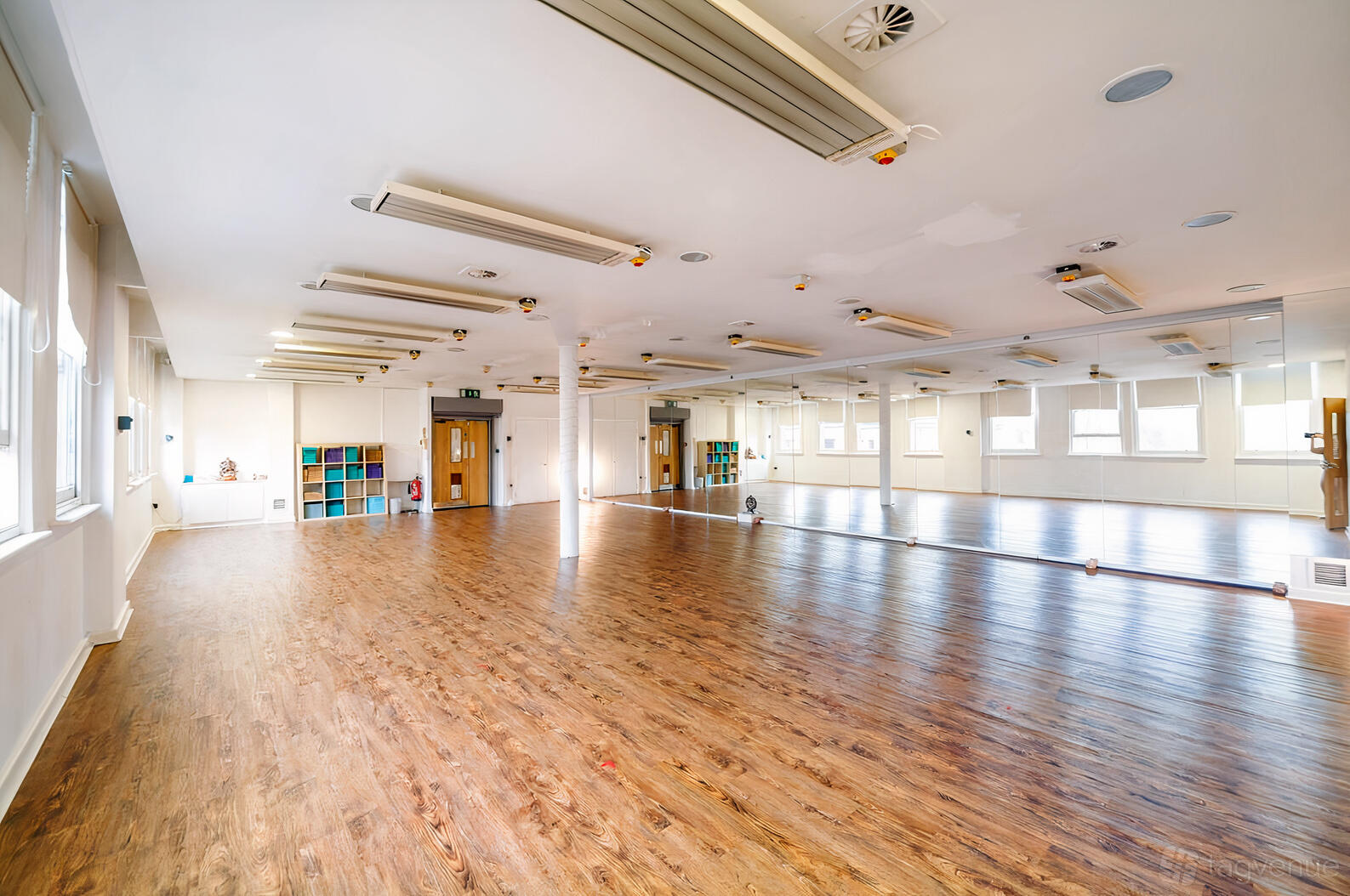 A yoga studio with wood floors, wall-length mirrors, and cubby shelving at The Life Centre North Manchester City Centre.