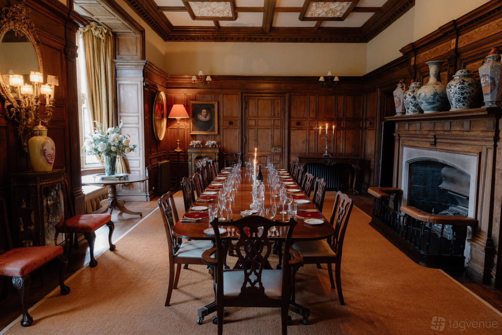 A castle dining room with oak-paneled walls, a long formal table set with glassware, and a large fireplace at Middleton Castle.