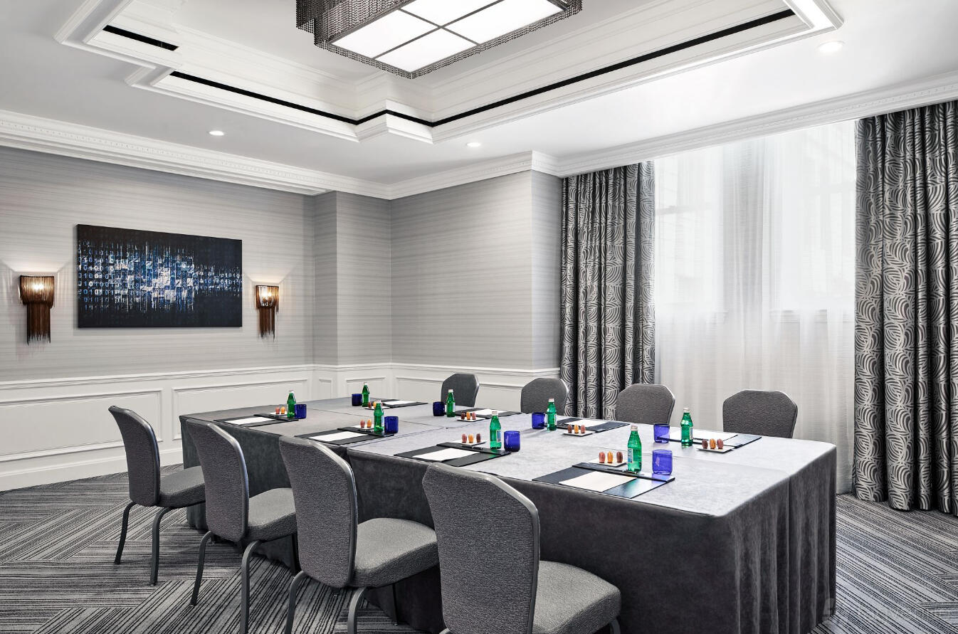 A hotel meeting room with a U-shaped table setup, grey chairs, and floor-to-ceiling windows at The Ritz-Carlton San Francisco.