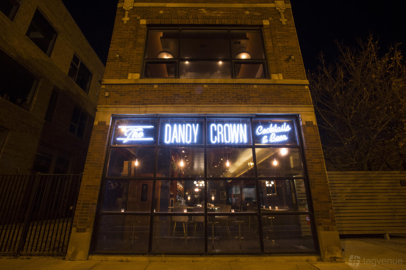 A restaurant with neon signage and floor-to-ceiling windows showing warm lighting at The Dandy Crown.