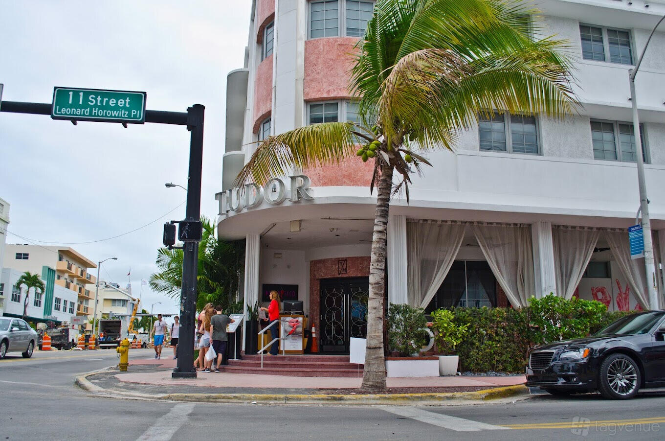 A restaurant with a corner entrance, large windows draped with white curtains, and palm trees at Naked Taco.