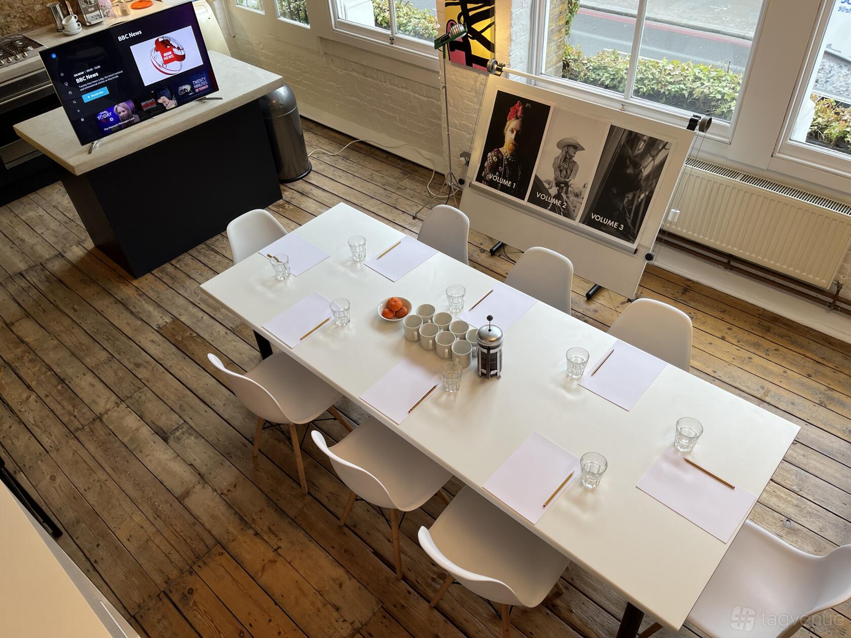 A meeting room with a long white table, wooden floors, and large windows at Unit Two