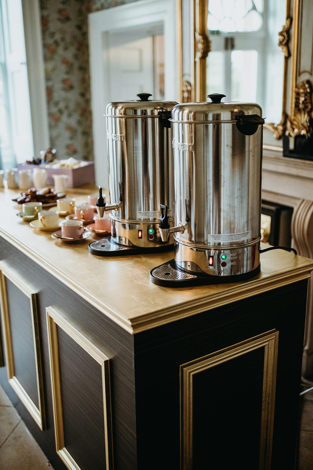 A refreshment station with coffee urns and pastel teacups on a gold-trimmed counter at Norwood Park Country House.