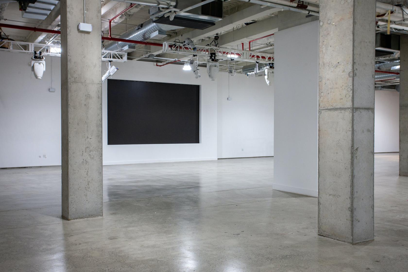 An event venue with polished concrete floors, exposed ceilings, and large pillars at Chelsea Industrial.