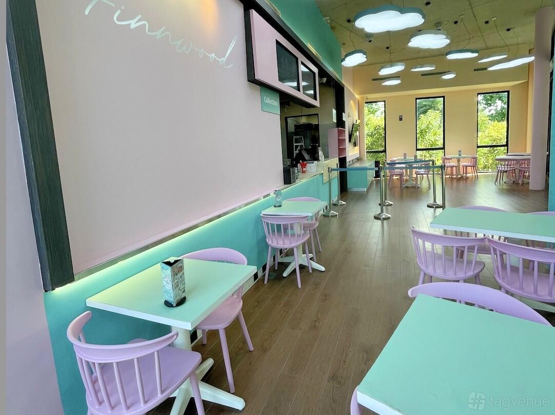 A cafe with pastel chairs, mint green tables, and ceiling lights shaped like clouds at Finnwood @ Children's Garden Cafe.
