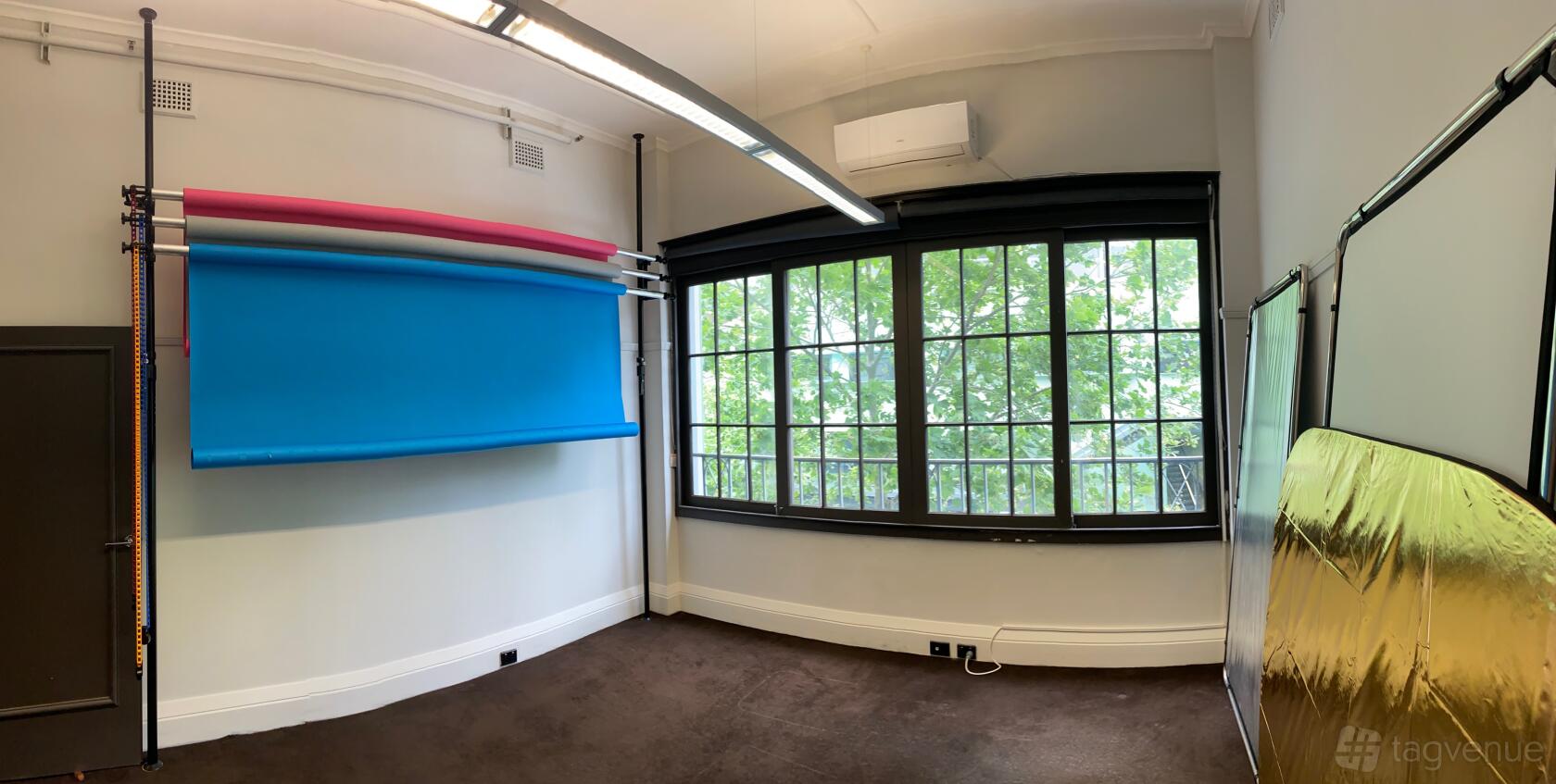 A photo studio with large windows, colored backdrop rolls, and metallic reflectors at Studio 2 Potts Point.