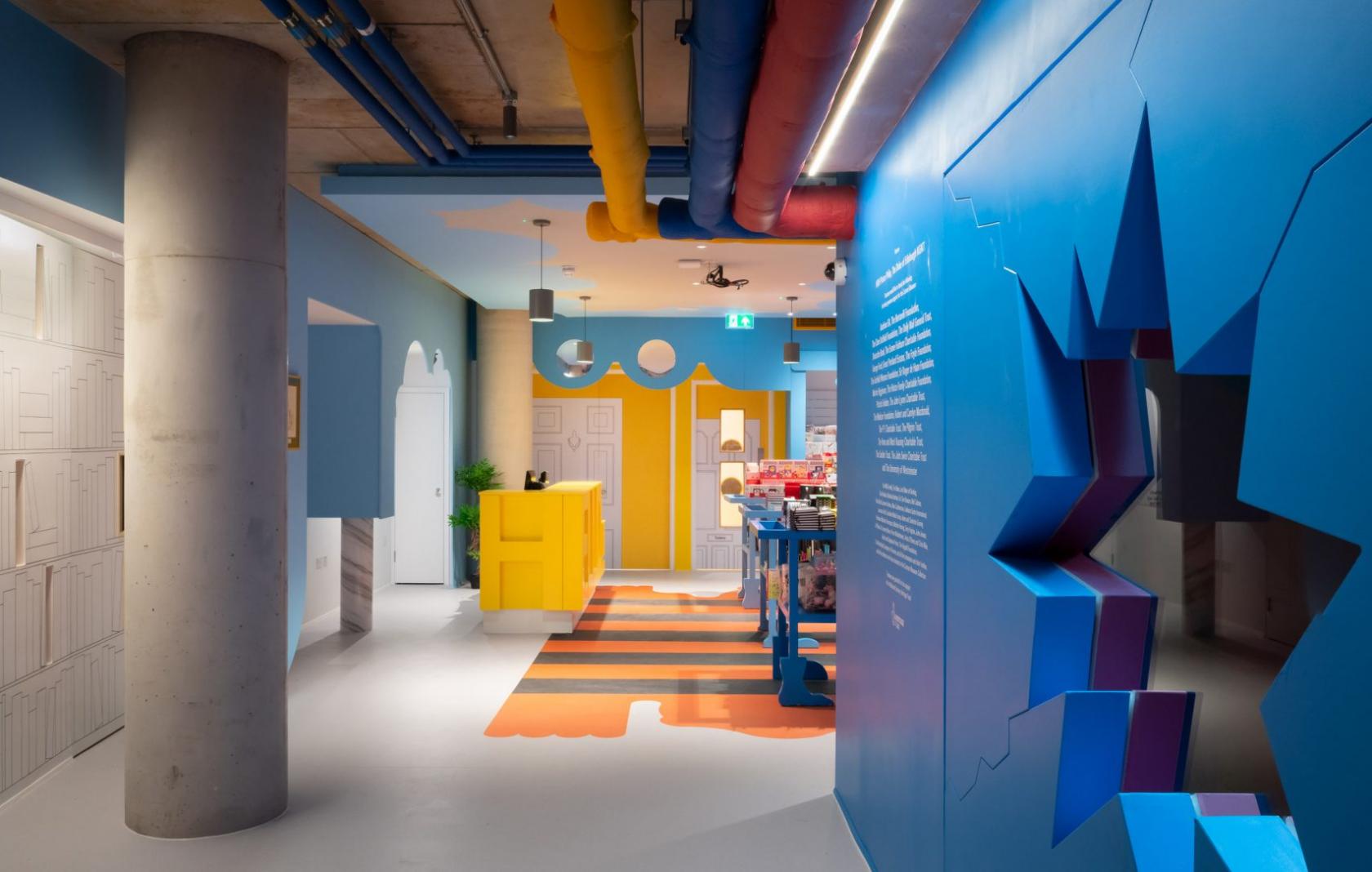A museum with colorful geometric wall art, exposed ceiling pipes, and modern displays at The Cartoon Museum.