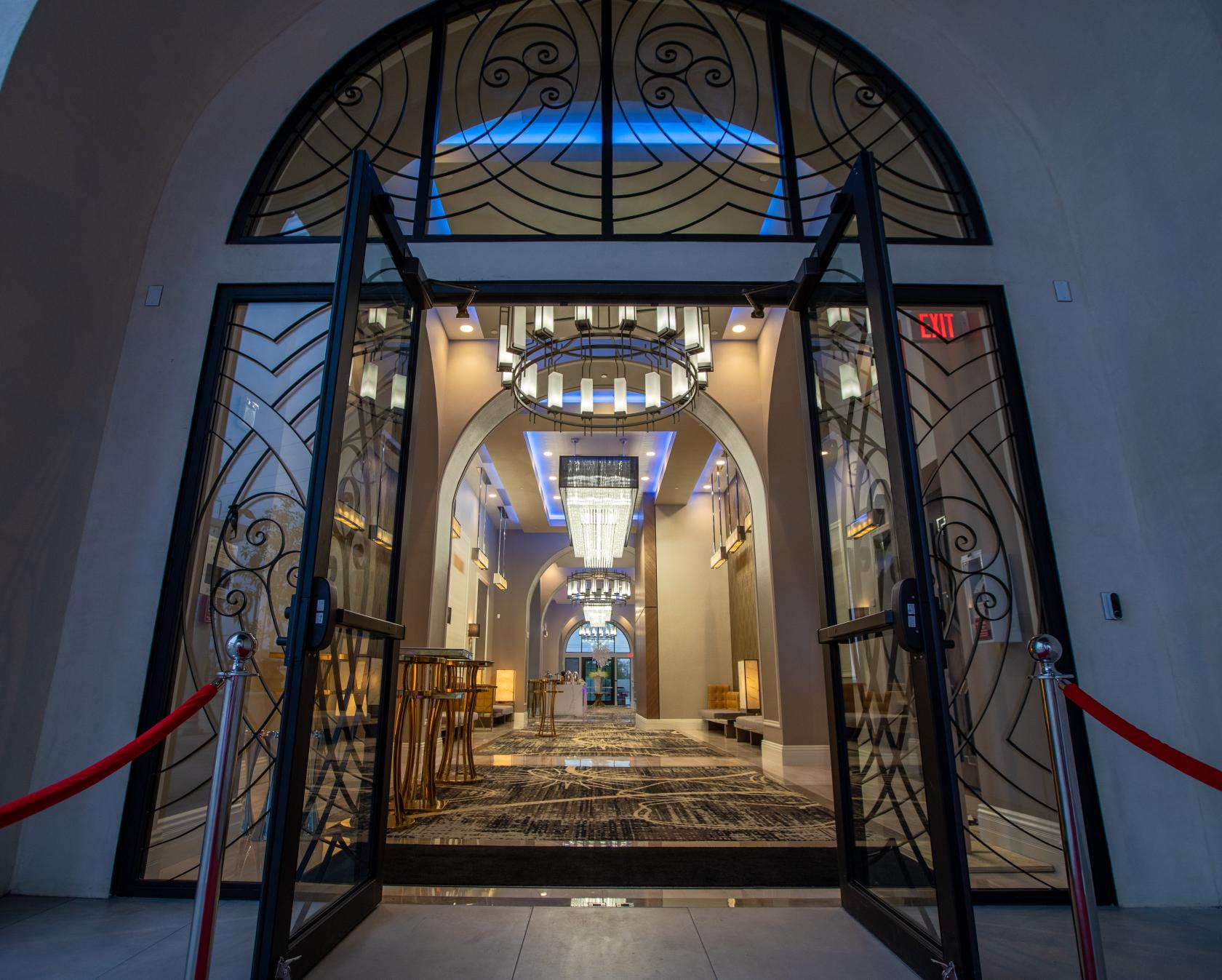 A grand hall with arched doorways, geometric glass entry, chandeliers, and patterned marble floors at The Landmark.