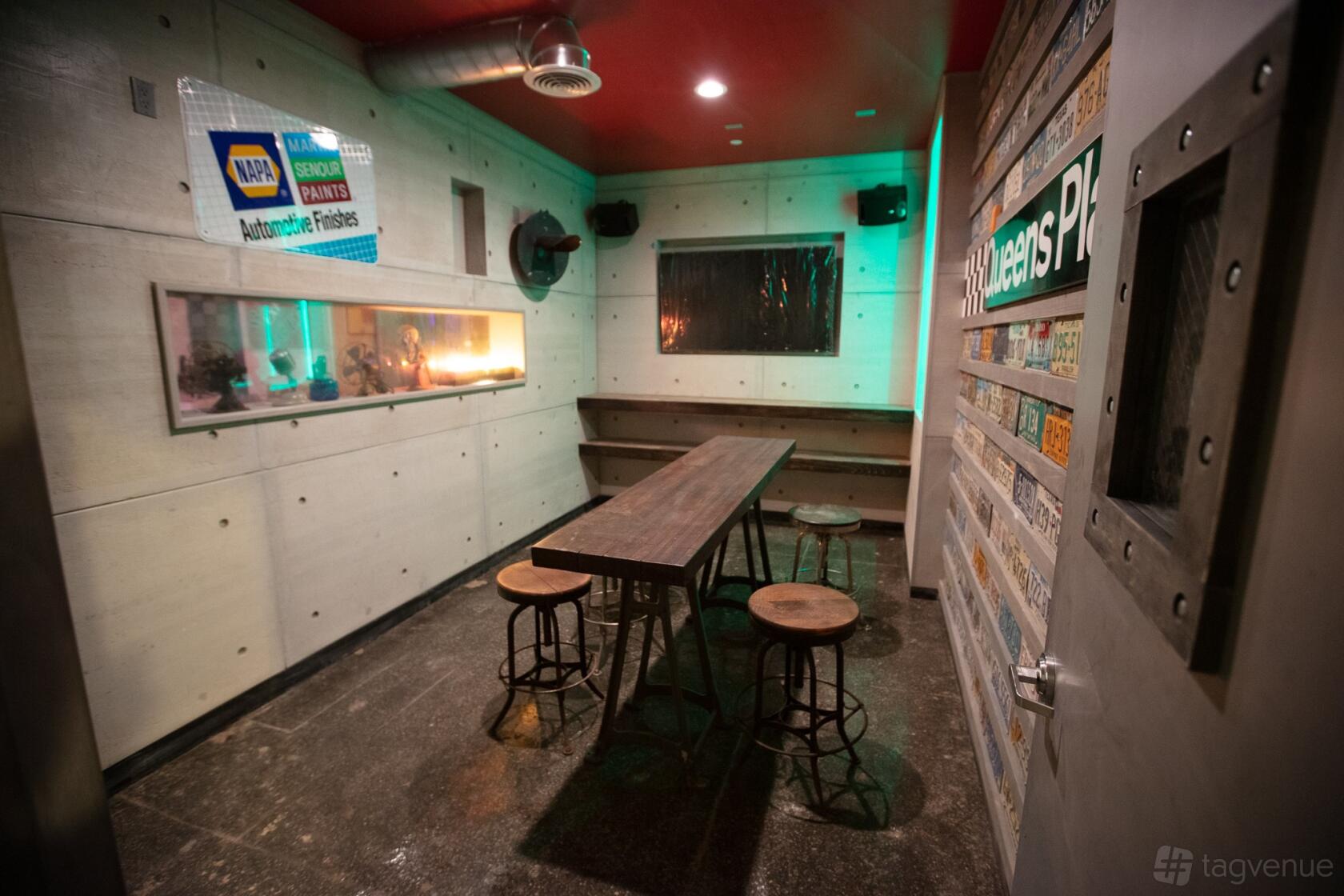 An industrial event venue with a long wooden table, metal stools, and vintage license plates on the wall at RPM Underground.