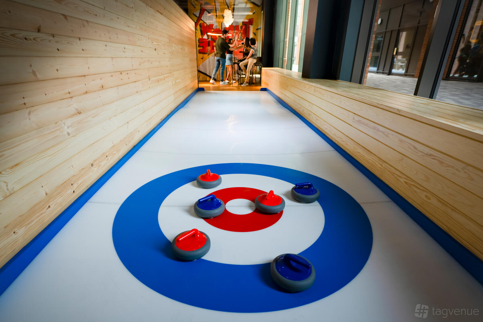 An event space with an indoor curling lane, wooden side panels, and curling stones at The Light Redhill.