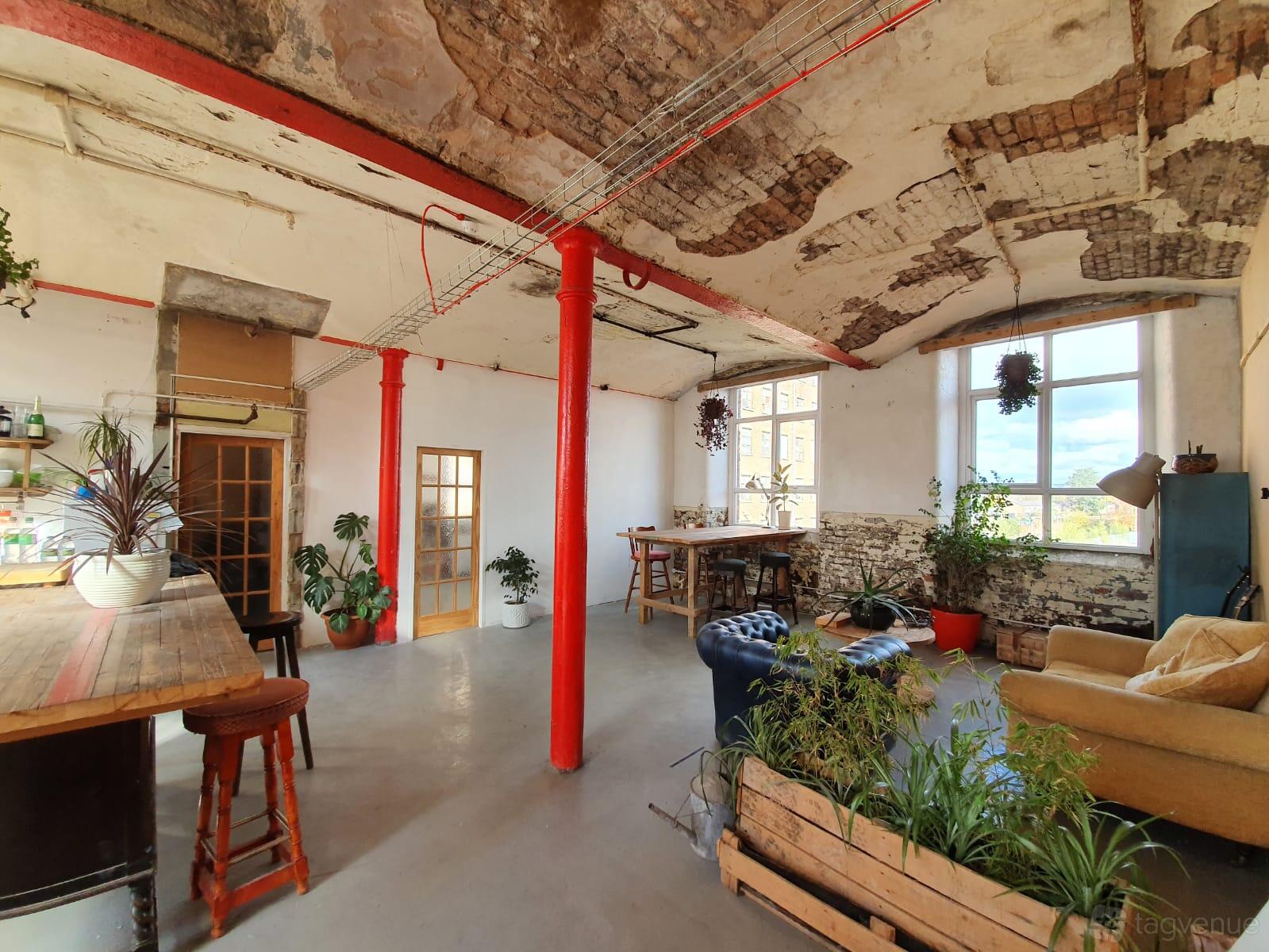 An art studio in a warehouse with exposed brick ceilings, large windows, and mixed seating at Wellington Studios.