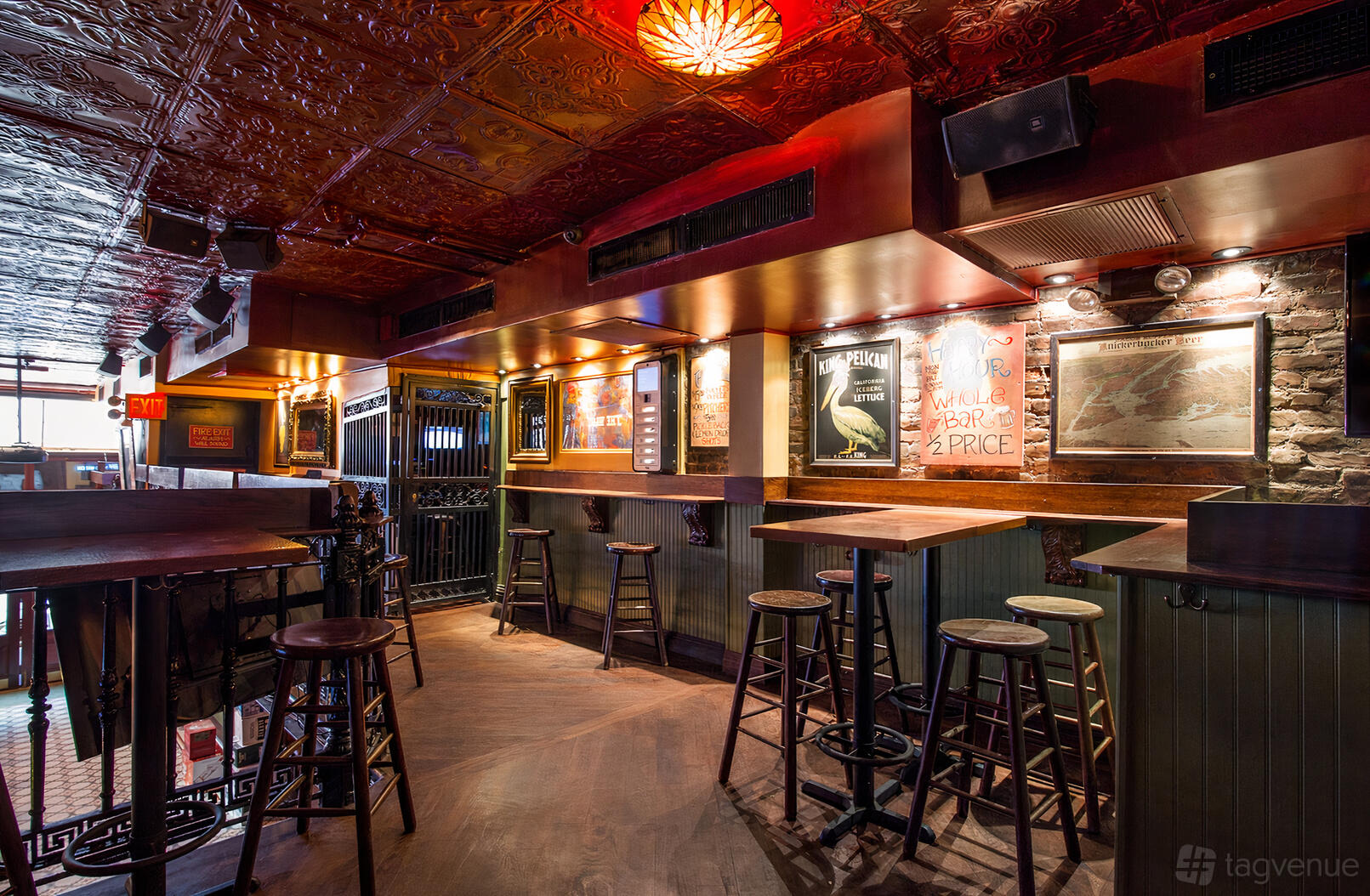 An event space in a bar with exposed brick walls, tin ceiling tiles, and tall bar stools at Off the Wagon.