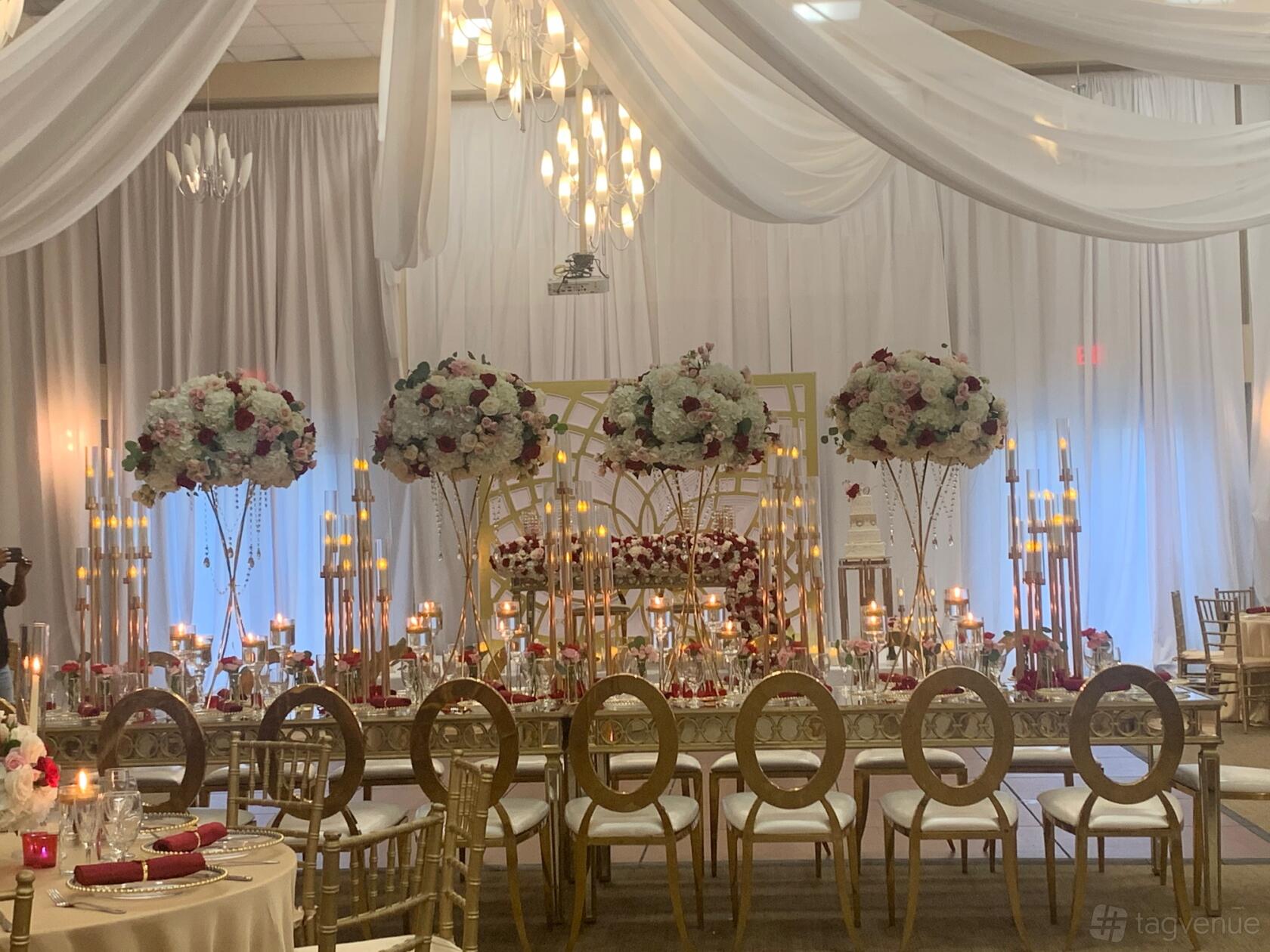 An event venue with draped white fabric ceilings, tall floral centerpieces, and gold chairs at Bonaventure Ballrooms.