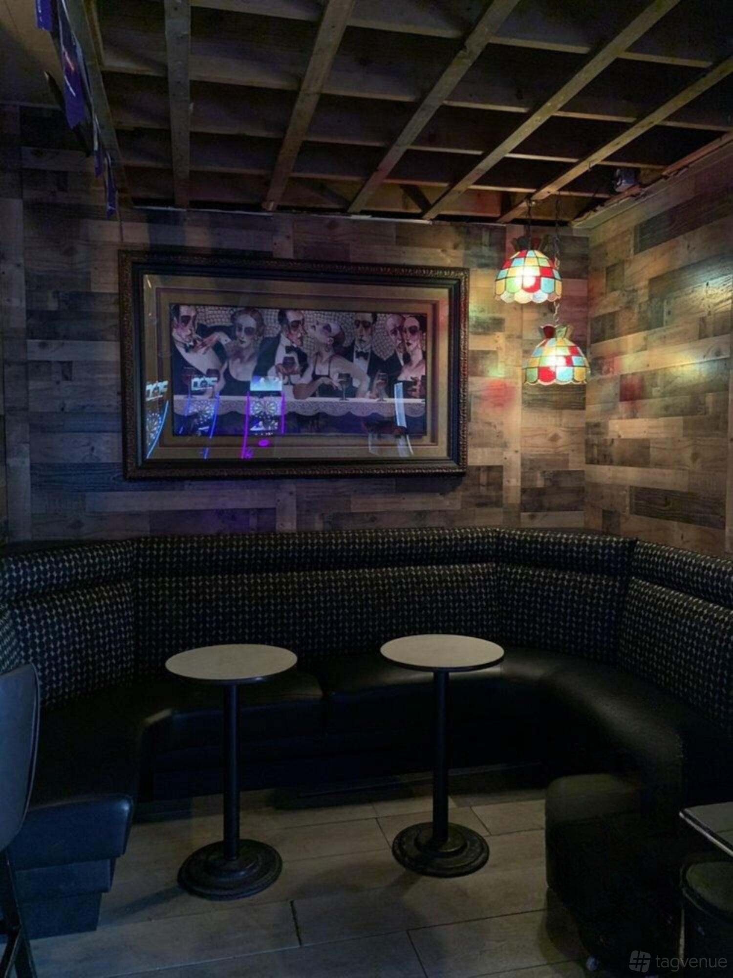 A bar lounge with wood panel walls, curved banquette seating, and small round tables at Squire's.