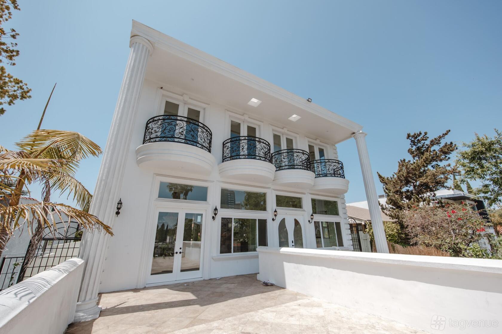 A film and photo studio with white exterior, tall columns, and wrought iron balconies at Century City Mansion.
