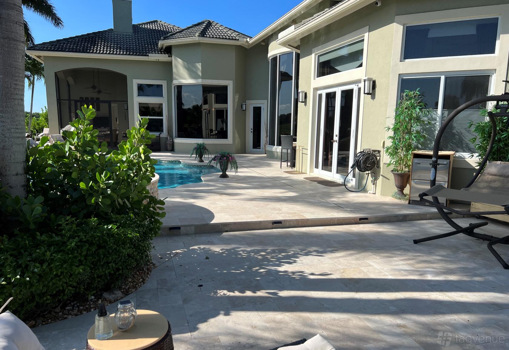 A country house with large windows, a private pool, and a spacious stone deck at Savvy Ventures Studios.