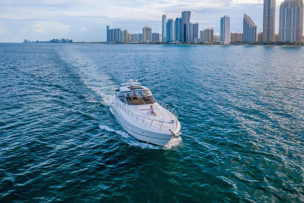 A white yacht cruising on open water with city skyline views in the background at Jerico Yacht Charters.
