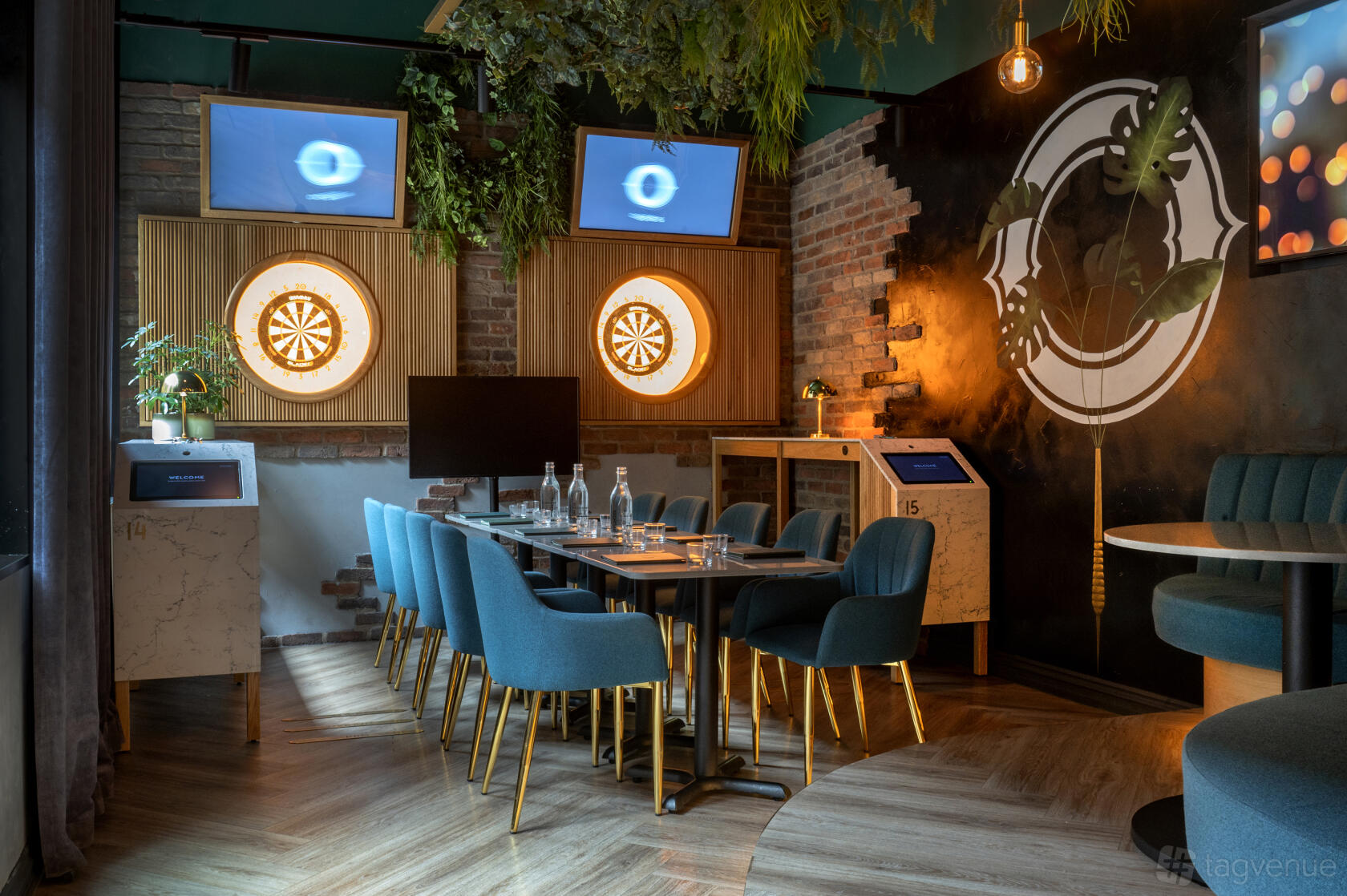 A bar with dartboards, teal upholstered chairs, and a long meeting table at Oche.