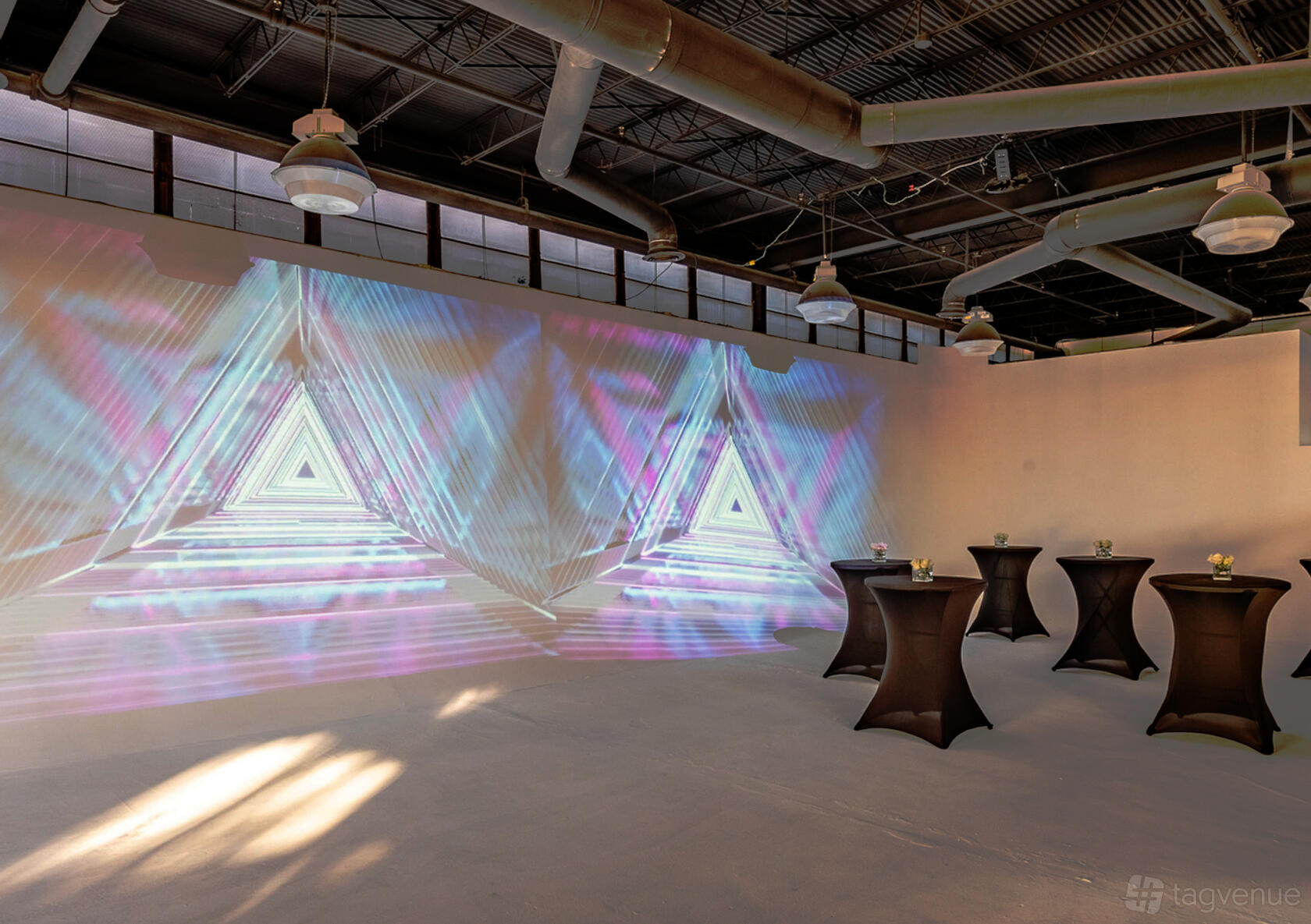 A photo studio with industrial ceilings, large upper windows, and geometric light projections at L.A.Y.D Spaces @ Maple Ave.
