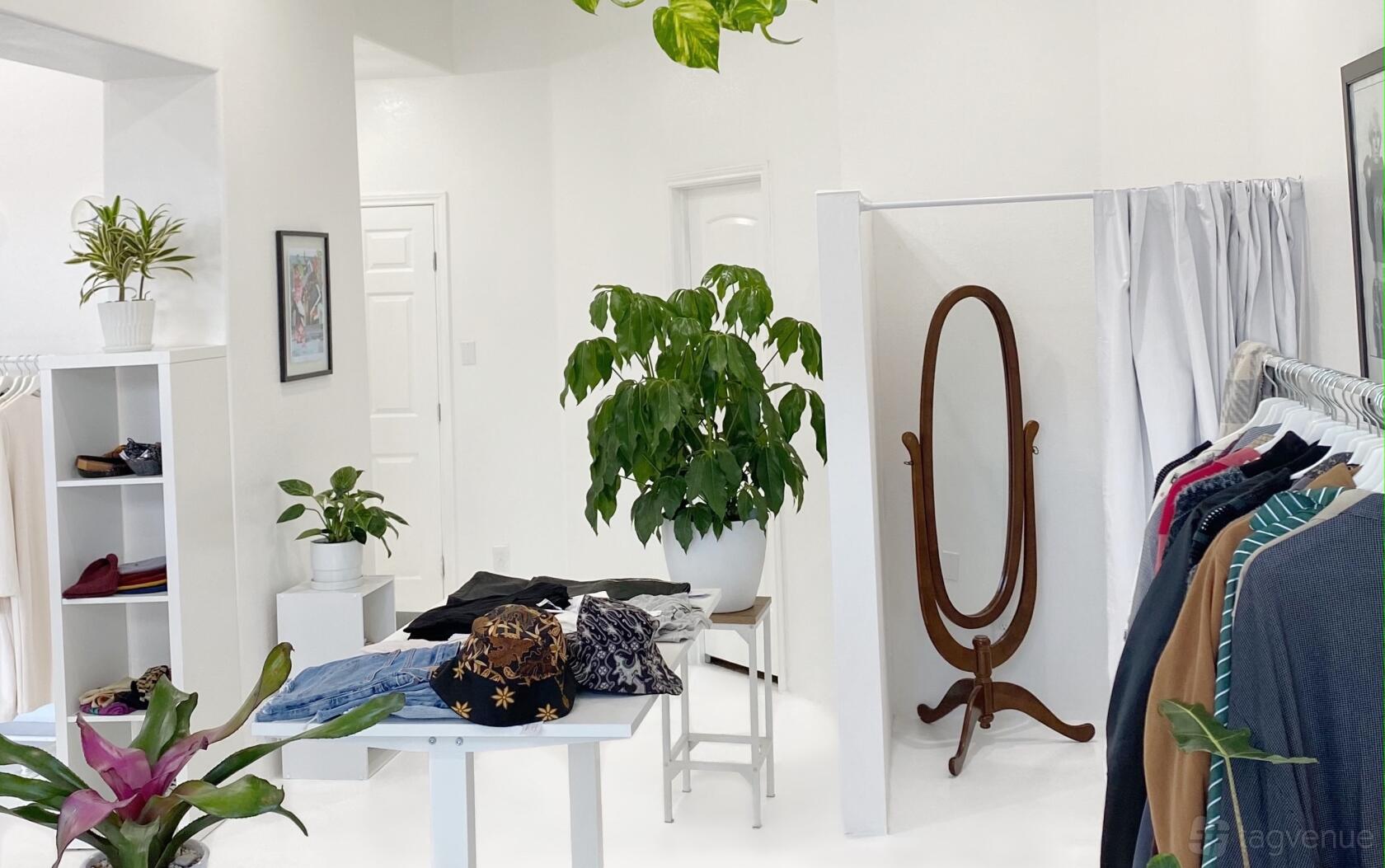 A photo studio with white walls, hanging plants, clothing racks, and a full-length mirror at Wonderlikewander.