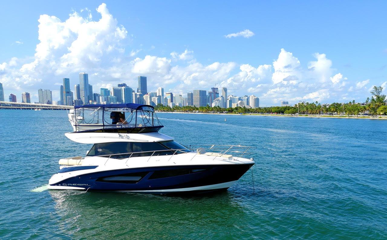 A yacht on open water with an upper deck lounge and city skyline views at Lots Of Yachts/Lots Of Spots South Florida.