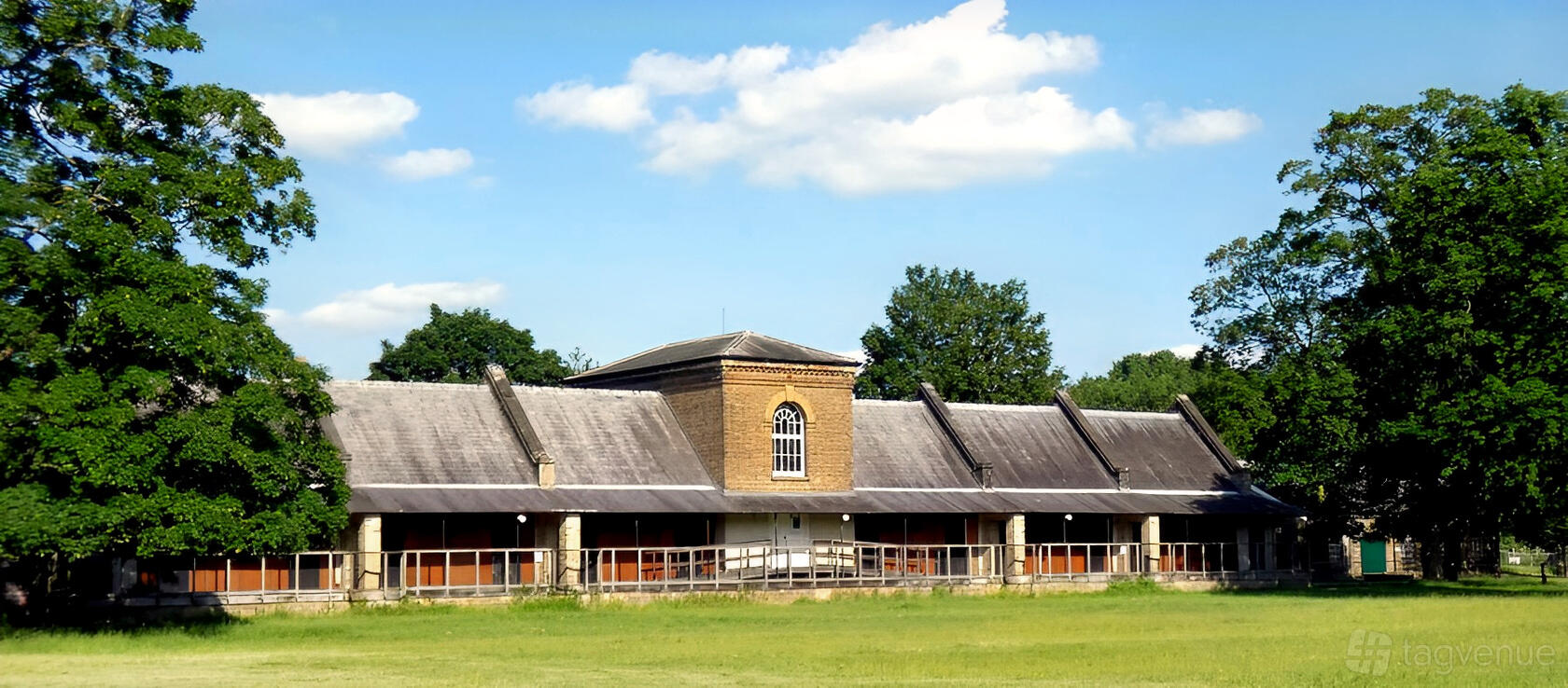 A museum with a historic brick building, large arched window, and pitched roof surrounded by green lawns at Royal Gunpowder Mills.