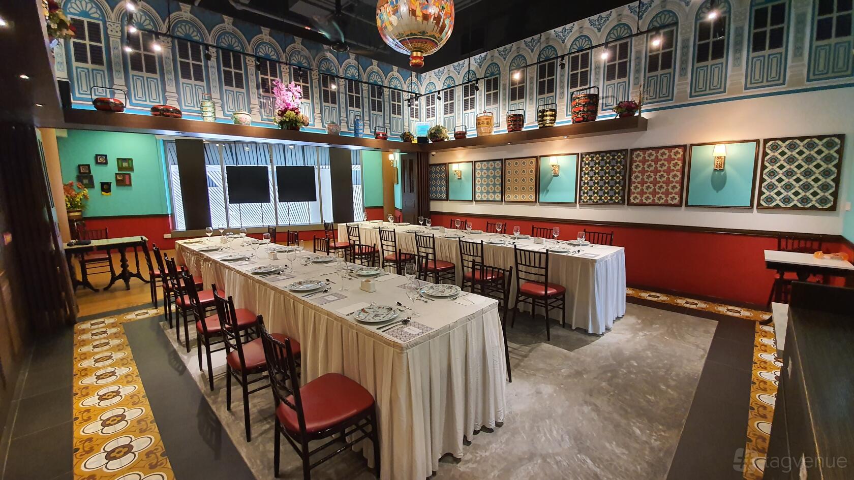 An event space with long banquet tables, red chairs, decorative tile flooring, and Peranakan accents at Straits Chinese Nonya Restaurant - Raffles.