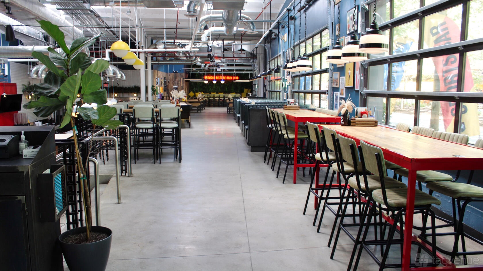 An industrial event space with large windows, exposed ductwork, high ceilings, and mixed seating at BrewDog Atlanta.