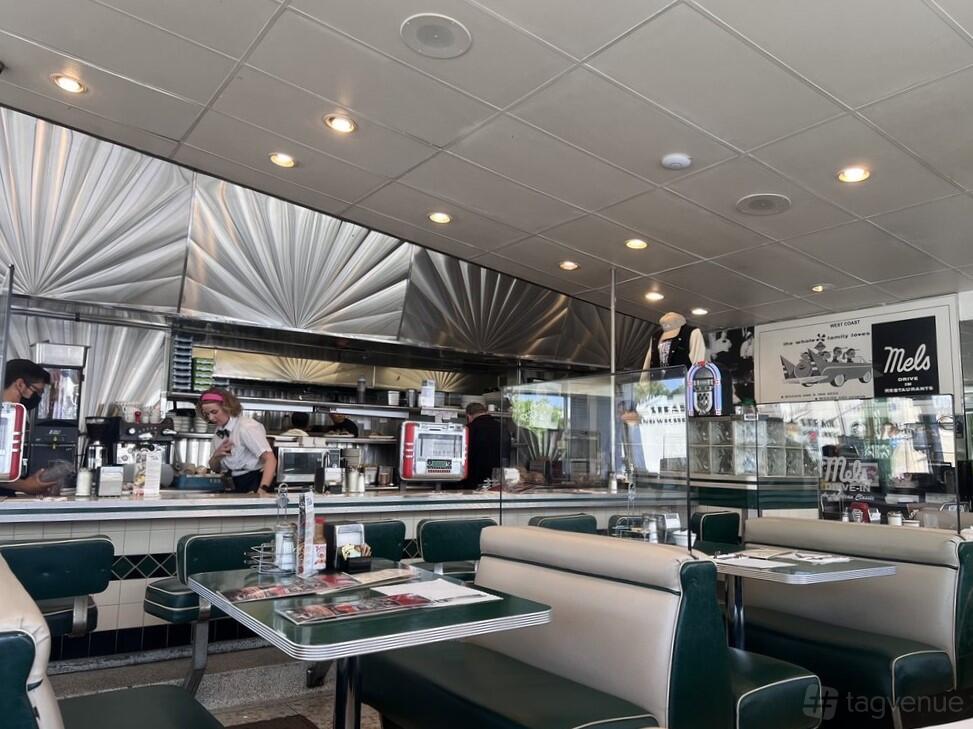 A retro restaurant with green vinyl booths, chrome accents, and an open counter at Mel's Drive-In Sherman Oaks.