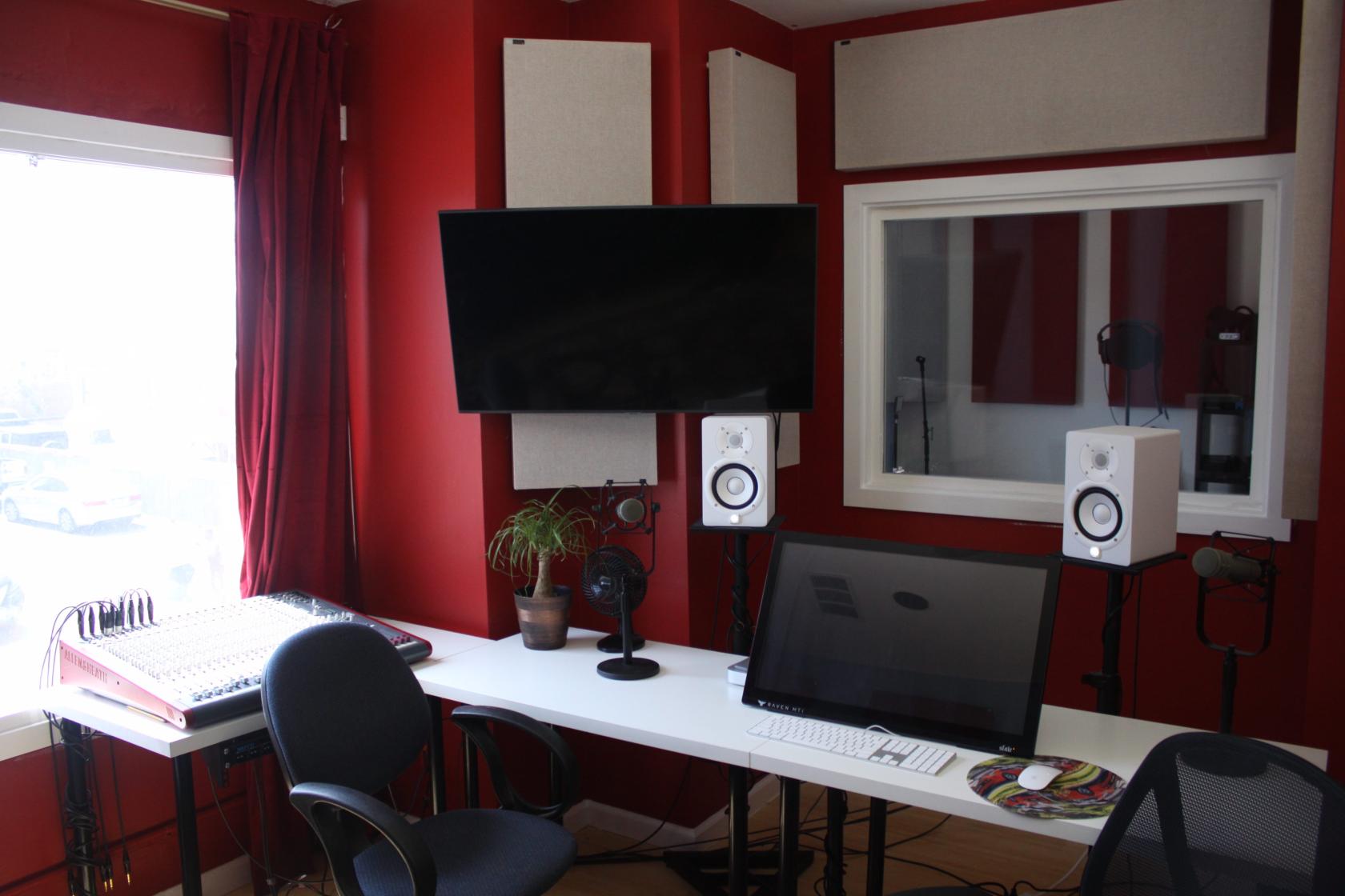 A community centre studio with a mixing console, soundproof panels, and computer monitors at The Music Company.