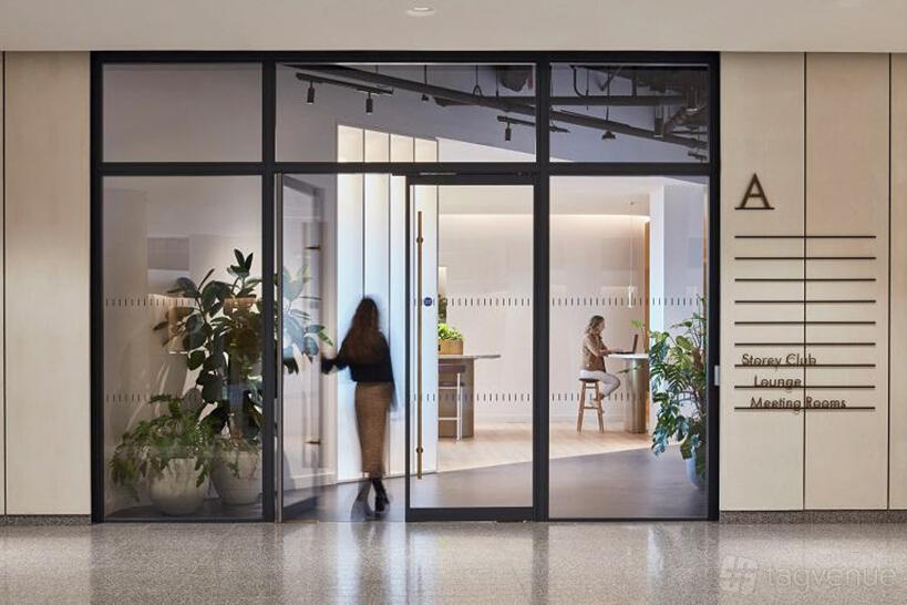 An auditorium entrance with glass doors, potted plants, and a view into a lounge at Storey Club Broadgate.