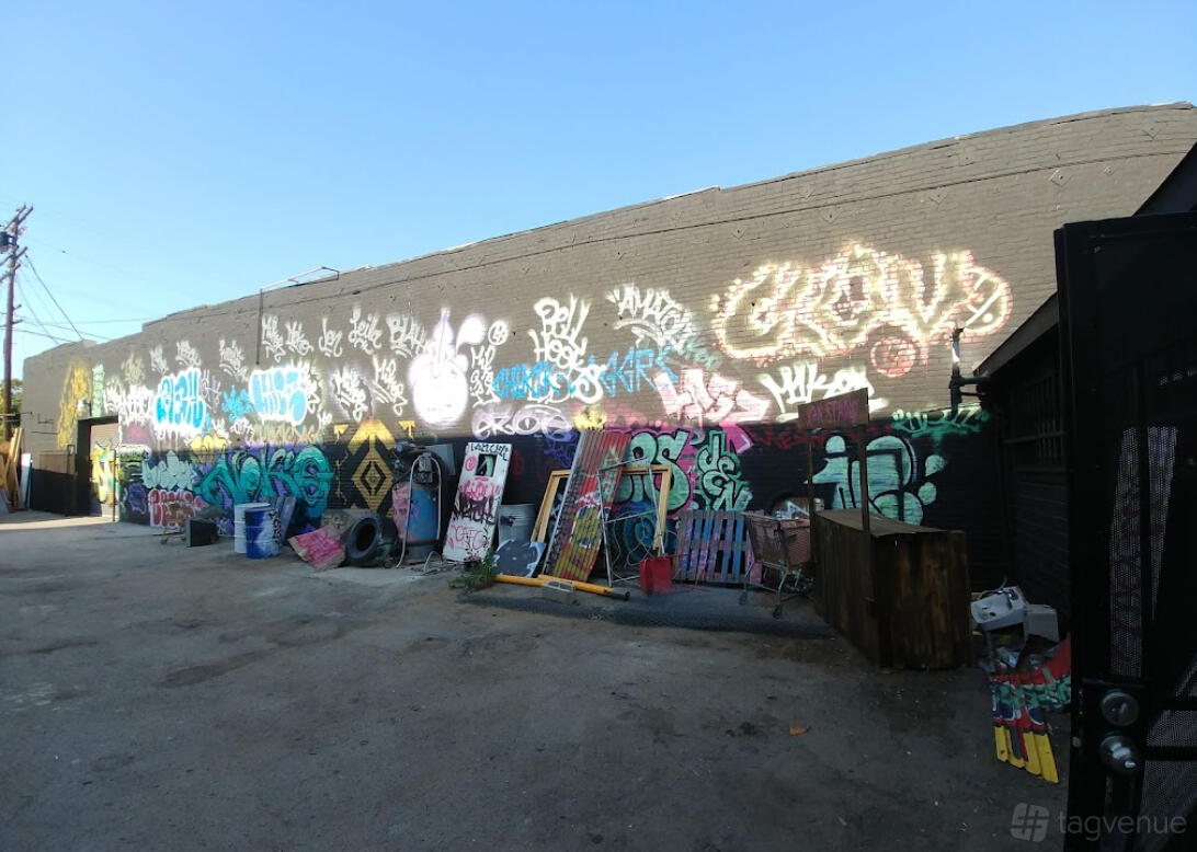 An outdoor photo studio lot with colorful graffiti murals covering a large brick wall at Electric Pony Studios - Graffiti Lot.
