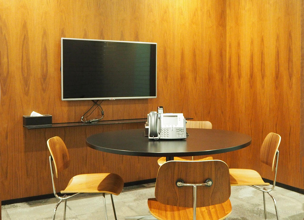 A meeting room with wood-paneled walls, a round table, four chairs, and a wall-mounted screen at Marina Bay Financial Centre Tower 1.