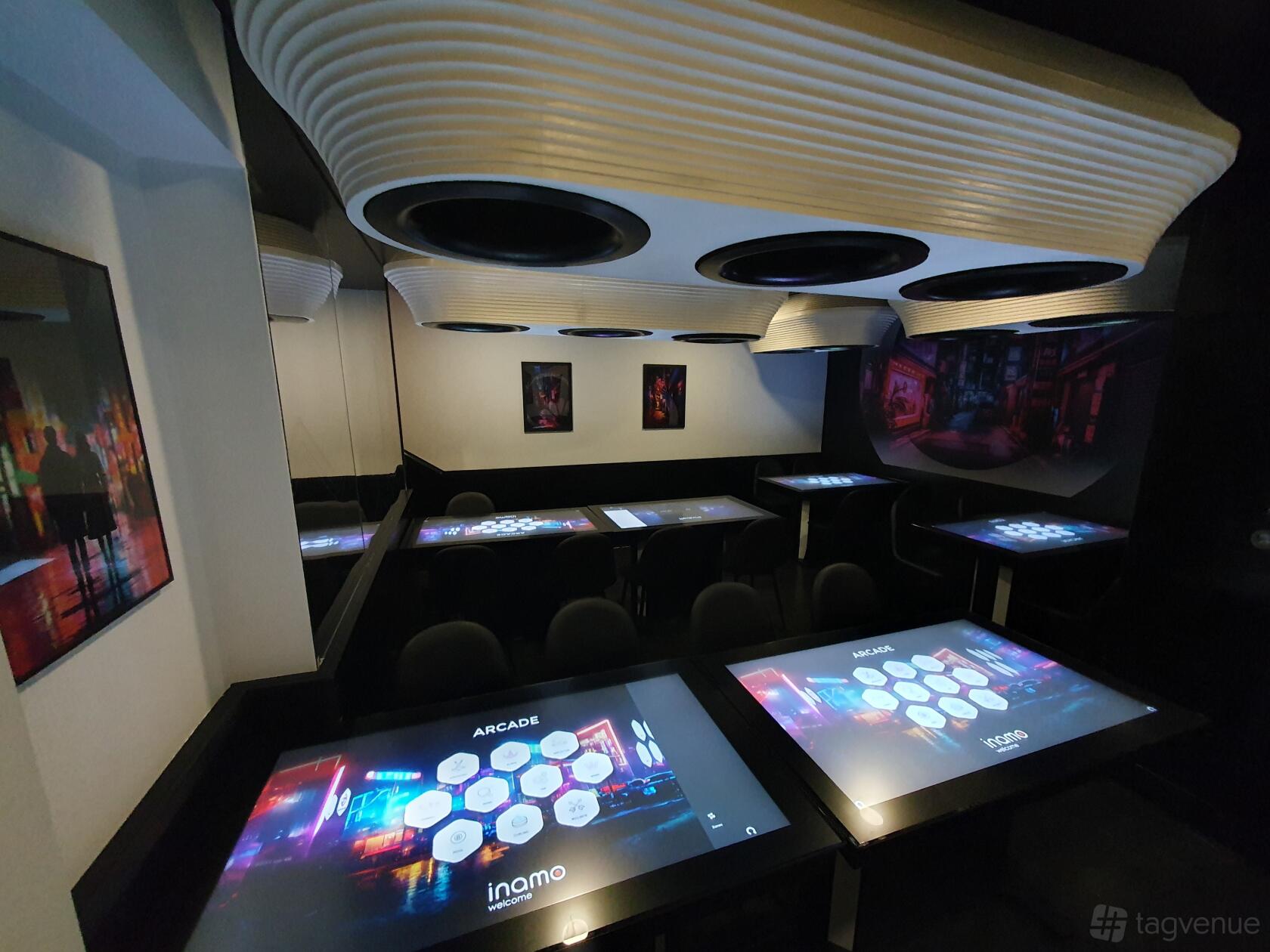 A dining room with interactive digital tables, curved ceiling panels, and wall art at Inamo Soho.