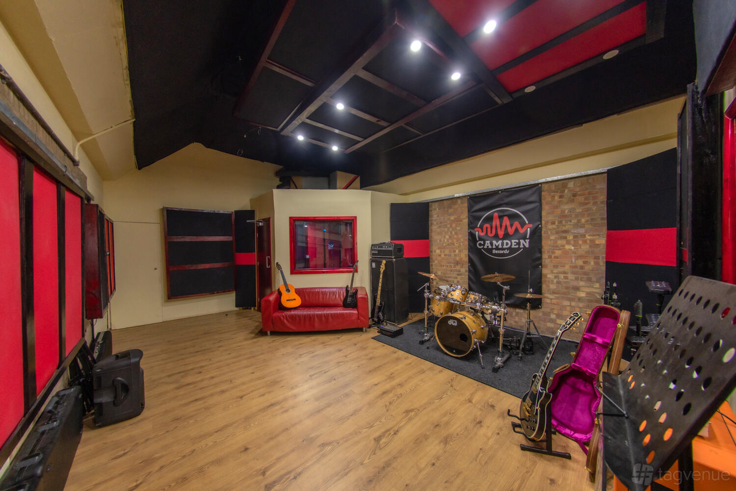 A recording studio with wood floors, musical instruments, a drum set, and soundproofed walls at Camden Records.
