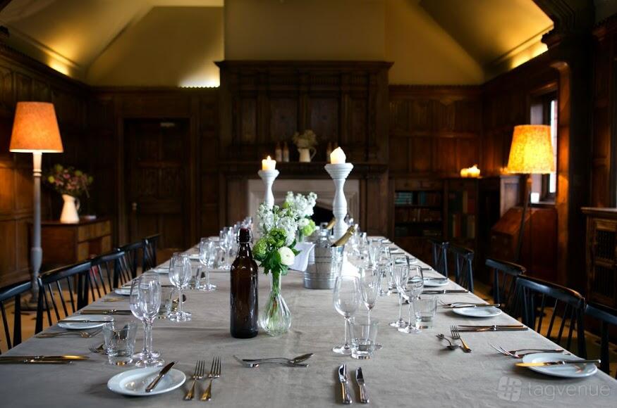 A hotel dining room with a long table set with glassware, candles, and floral centerpieces at The Olde Bell
