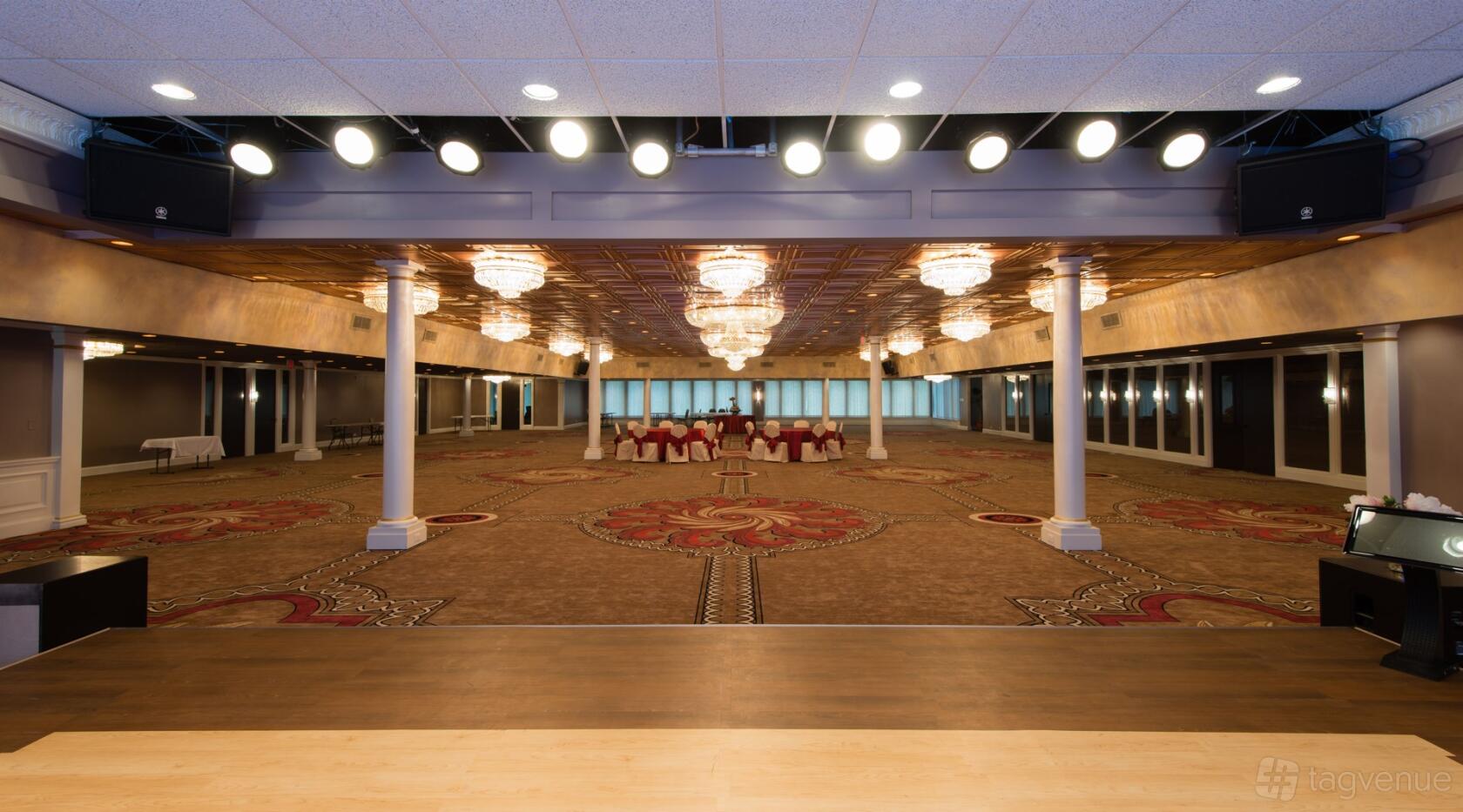 An expansive event hall with ornate chandeliers, decorative carpet, and a large open floor at Stone Ridge Event Center.