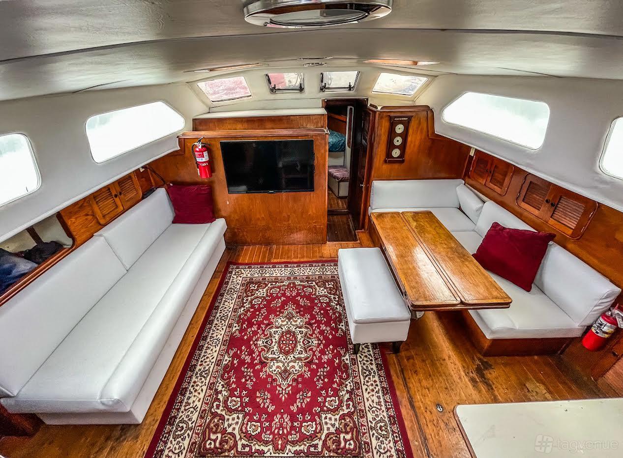 A boat interior with wood paneling, white cushioned seating, a dining table, and skylights at Charters 2000.