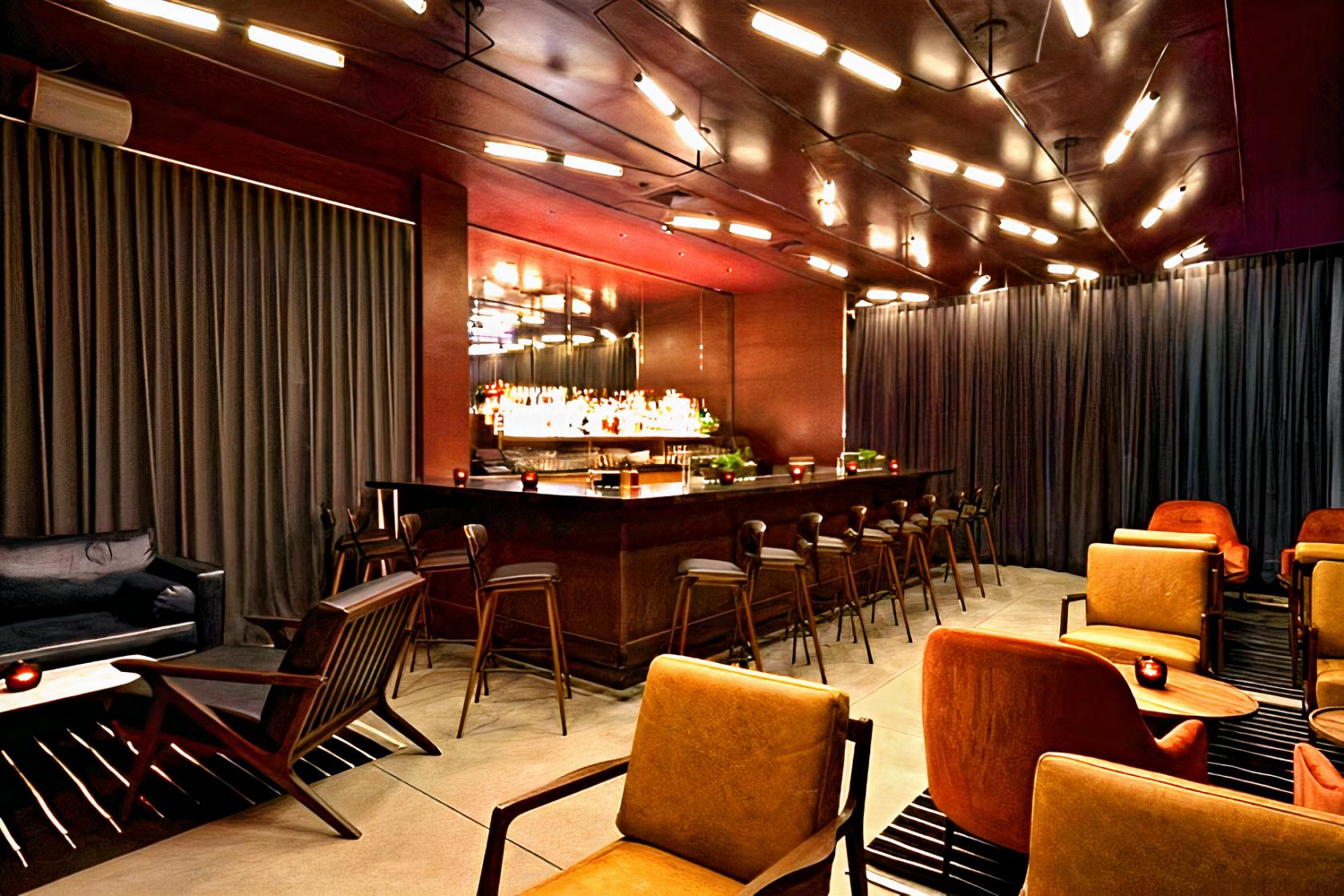 A hotel bar with a mirrored back bar, modern lighting, and velvet lounge seating at Arlo Soho.