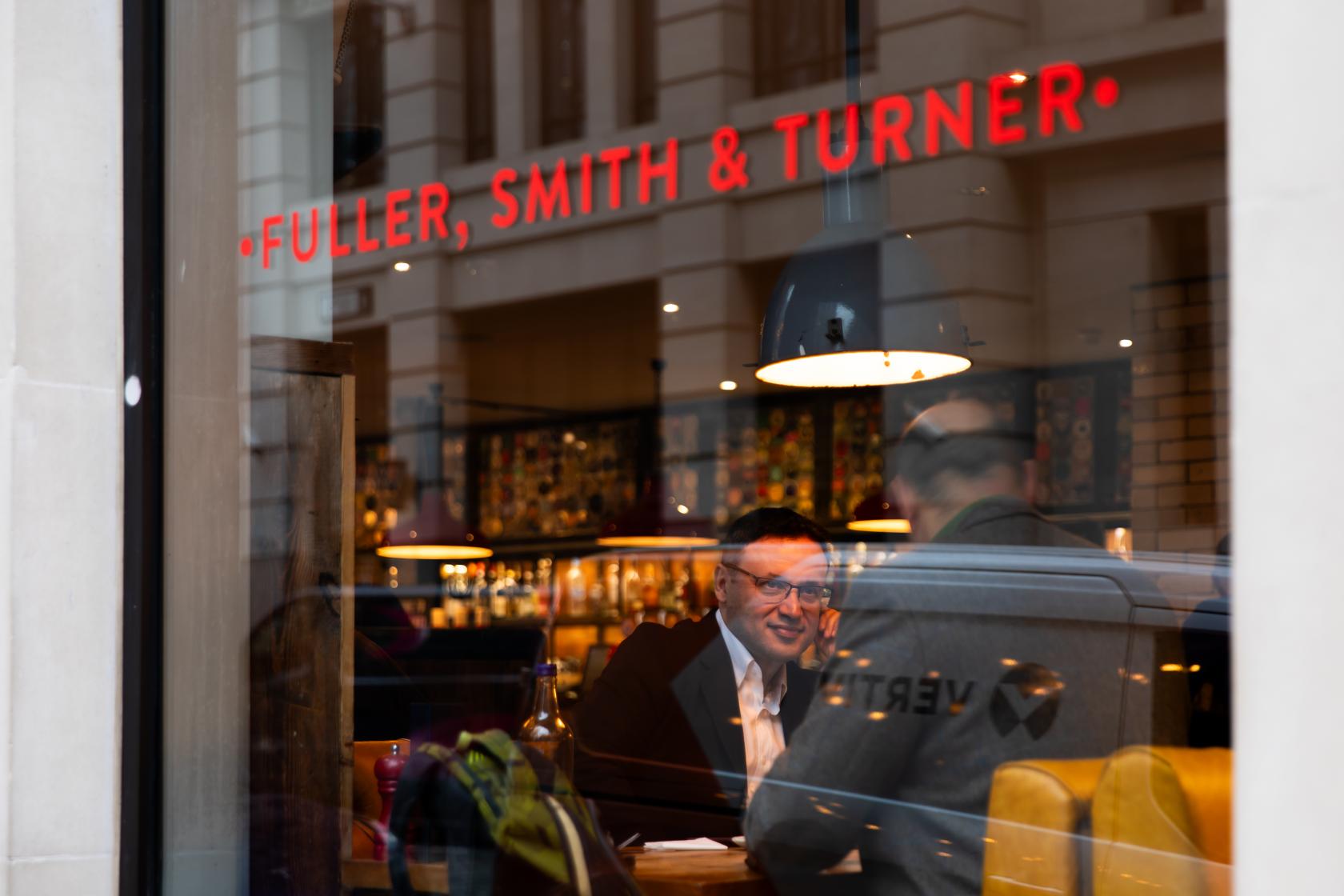 A pub with large street-facing windows, hanging pendant lights, and visible bar shelves at The Hydrant.