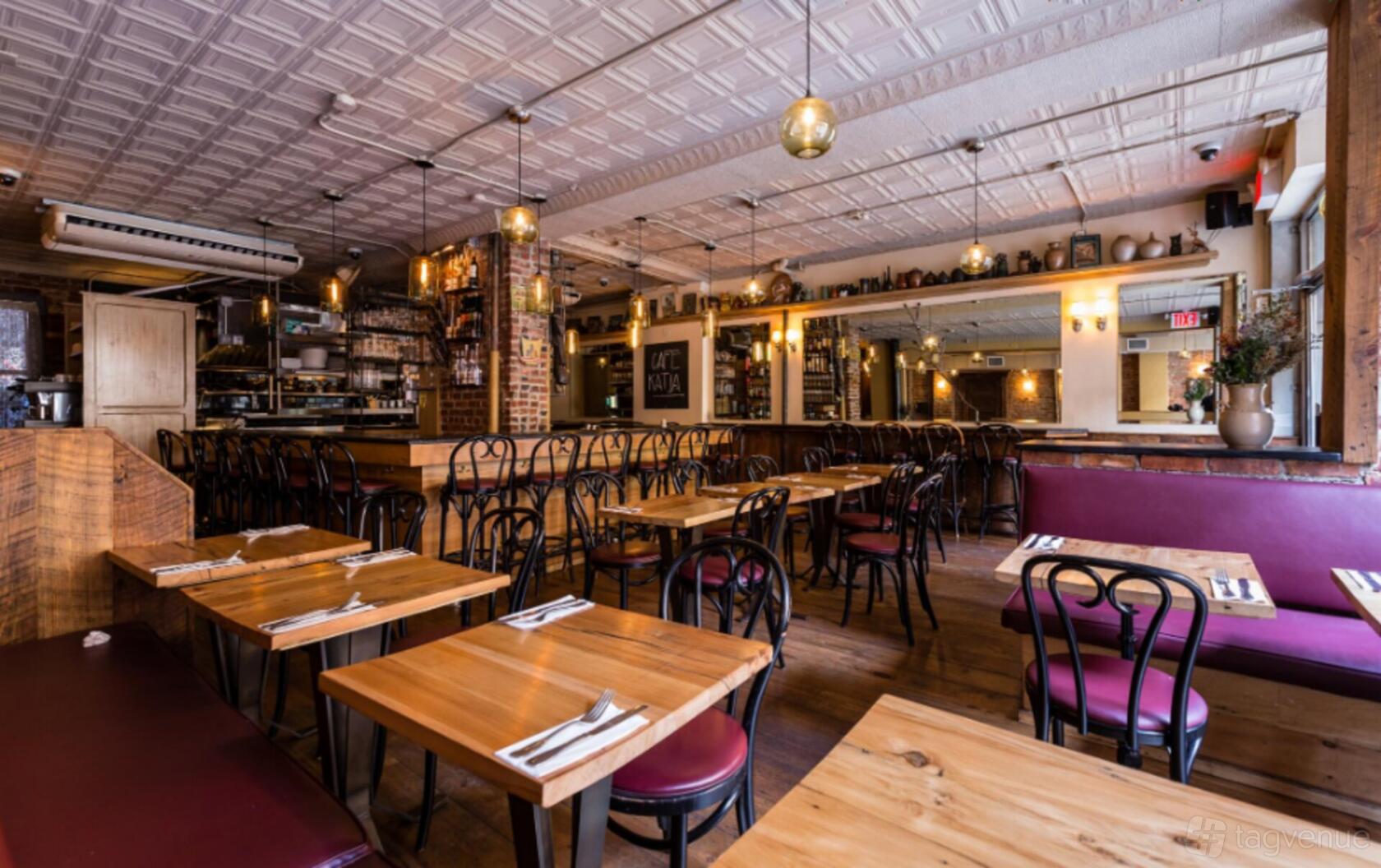 An event space in a restaurant with wooden tables, bentwood chairs, booth seating, and pendant lighting at Cafe Katja.